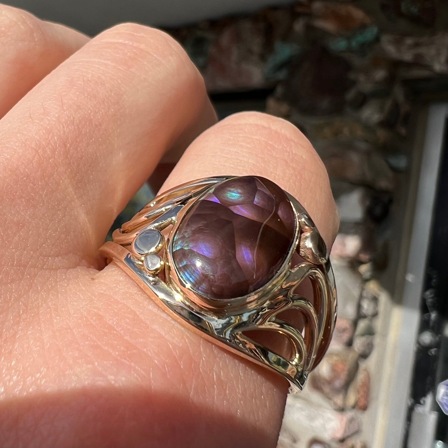 An oval cabochon cut fire agate with purple and blue colors set in a yellow gold men's ring.