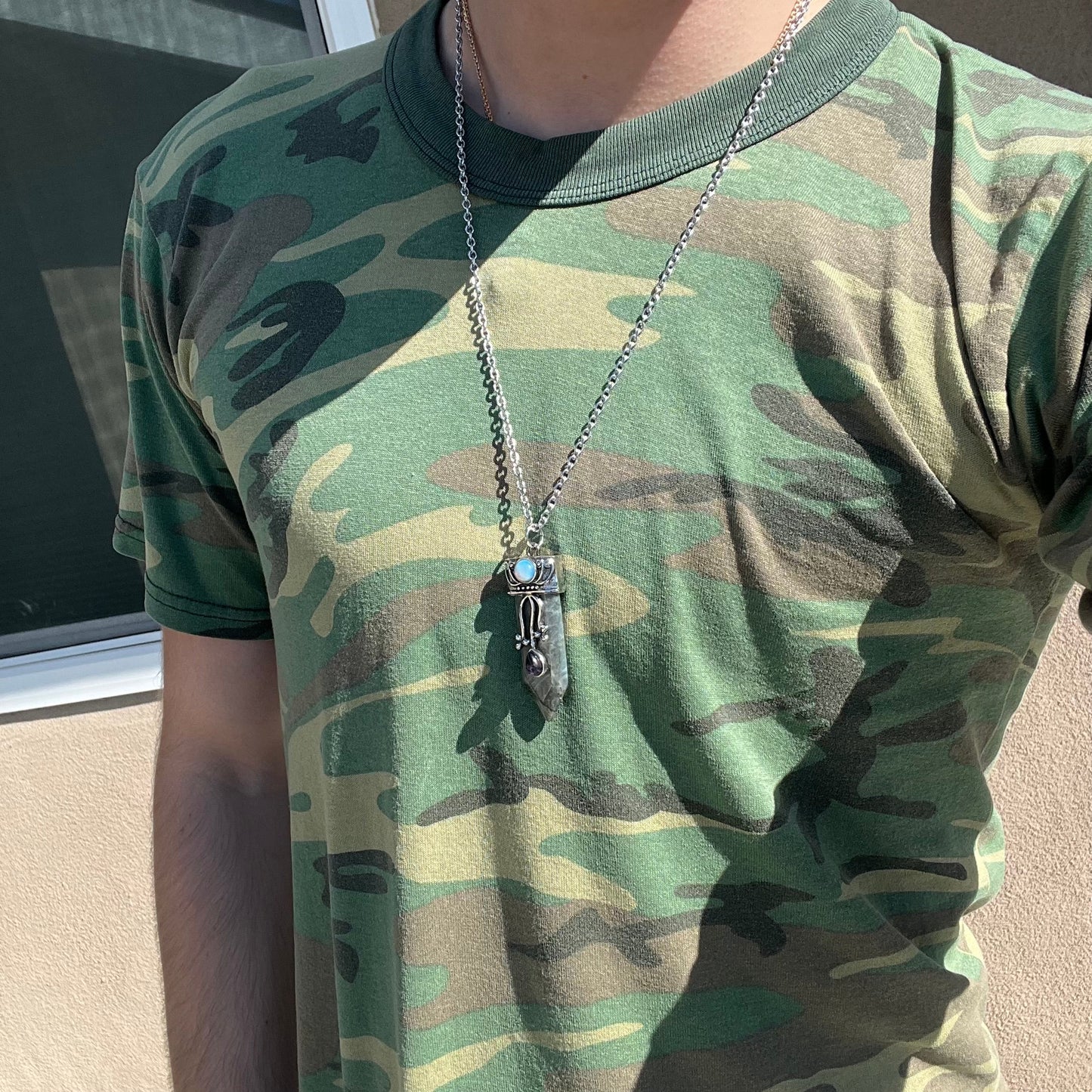 A stainless steal necklace set with a crystal shaped labradorite stone, purple glass, and an opalite accent.