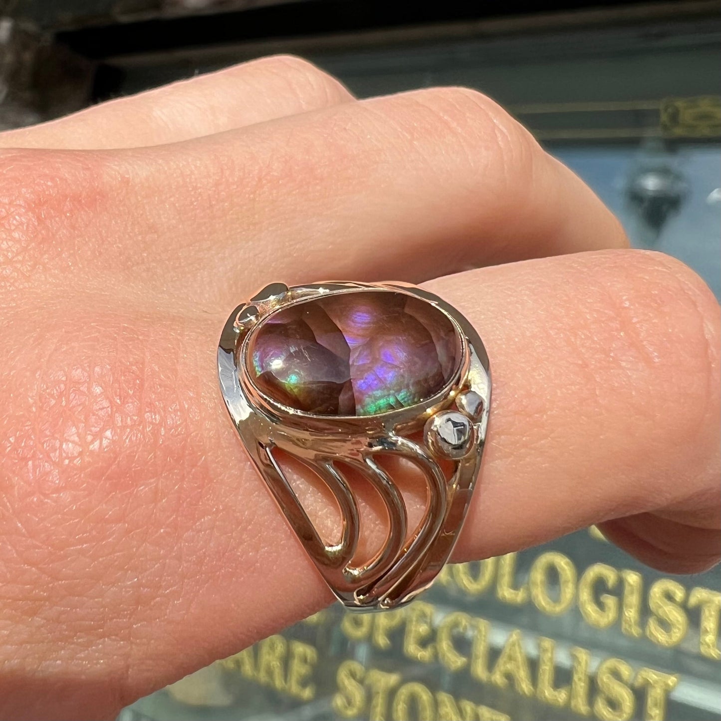 An oval cabochon cut fire agate with purple and blue colors set in a yellow gold men's ring.