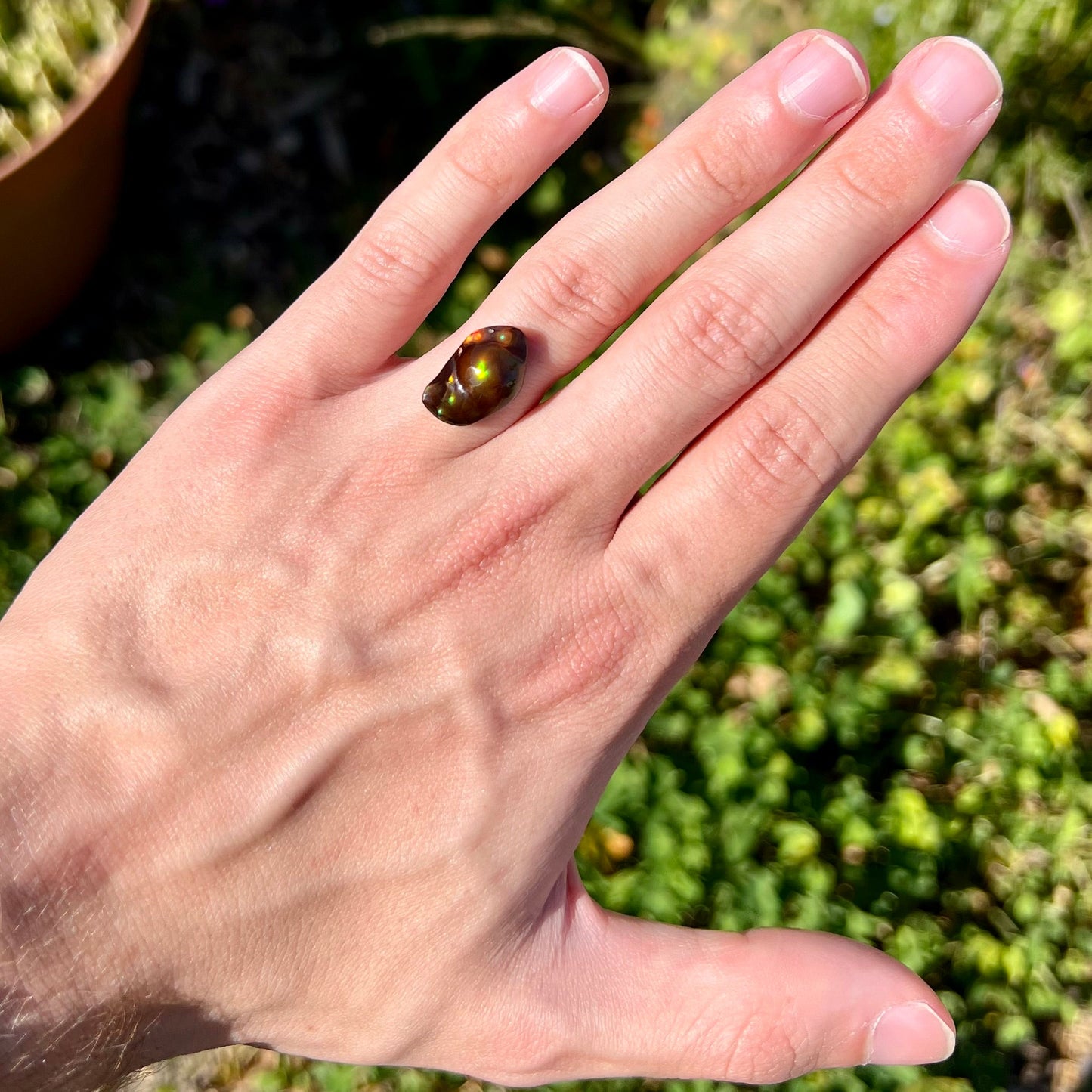 A loose fire agate stone. The stone has a rainbow of metallic iridescence.