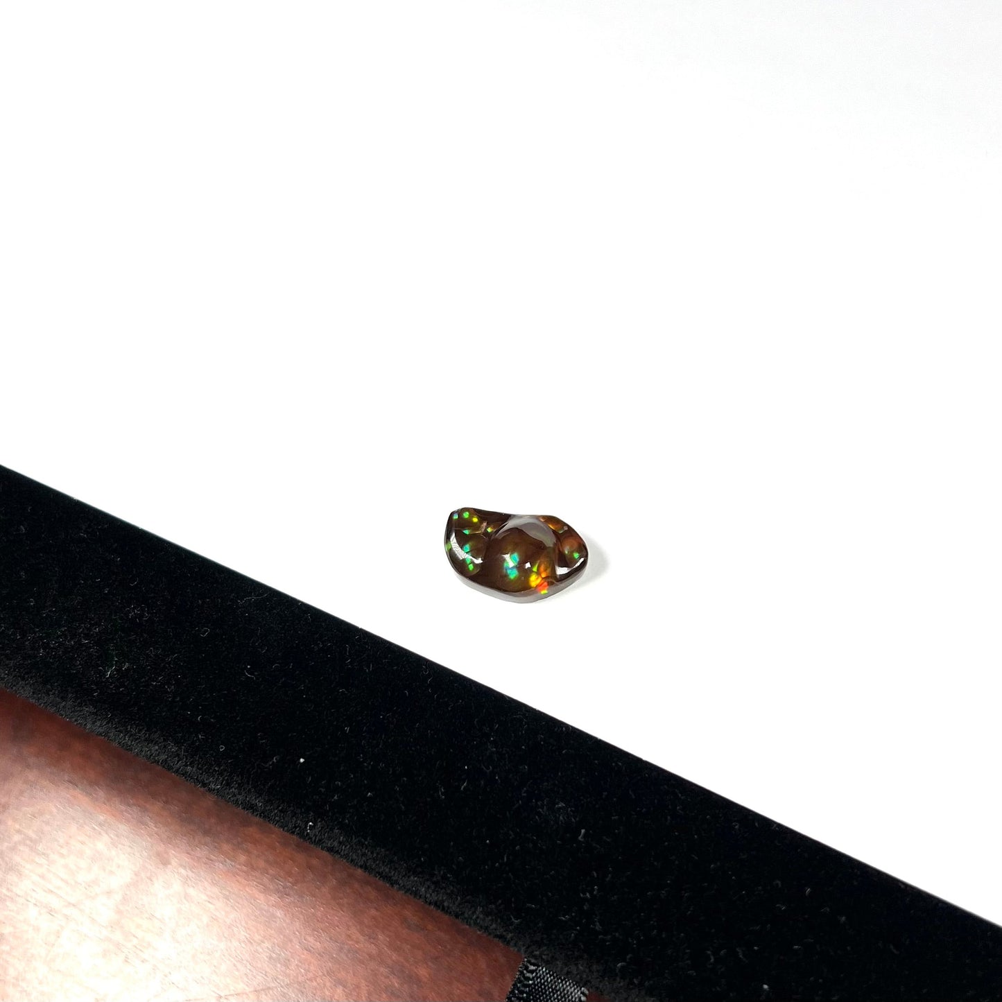 A loose fire agate stone. The stone has a rainbow of metallic iridescence.