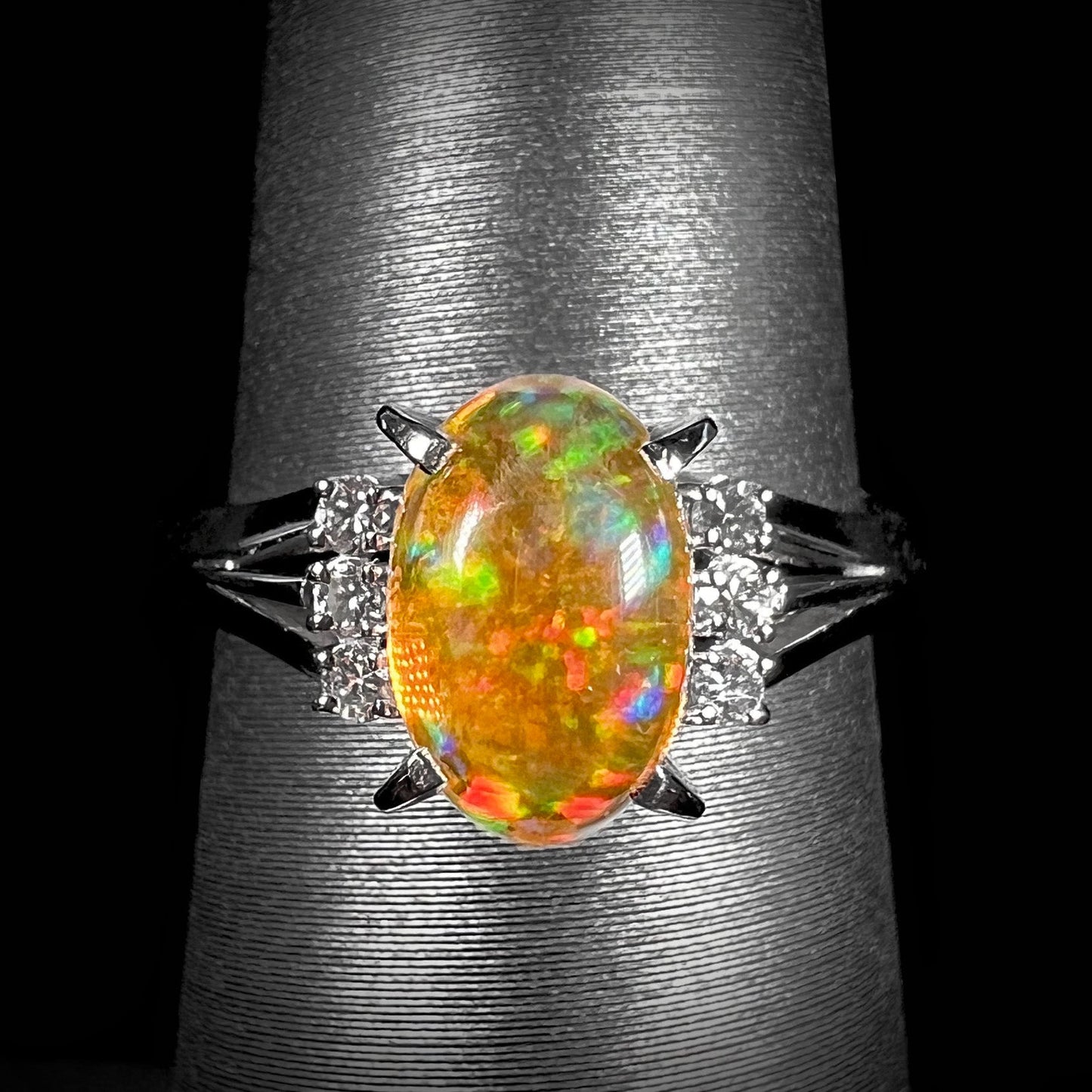 A platinum filigree and diamond-accented Mexican fire opal ring. The opal is orange with green fire.