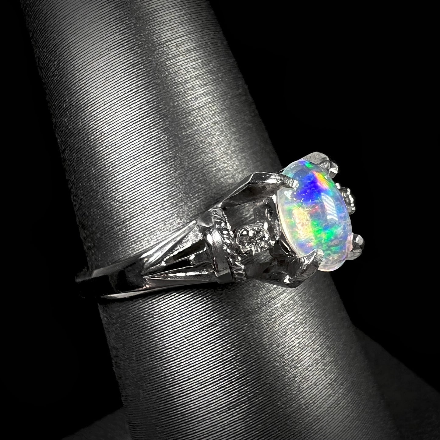 A platinum Mexican jelly opal ring with diamond accents. The ring has a rope textured design.