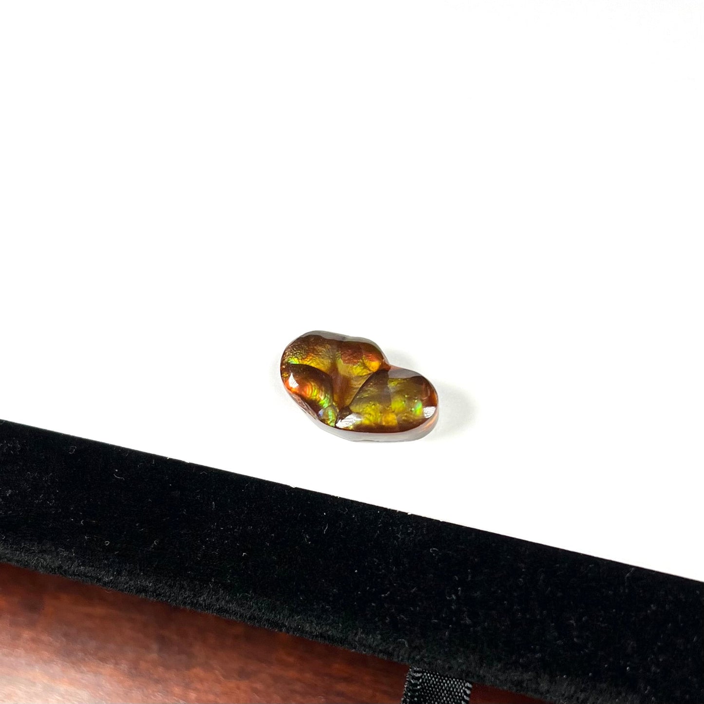 A loose, freeform shaped Mexican fire agate. The stone has green and orange iridescence.