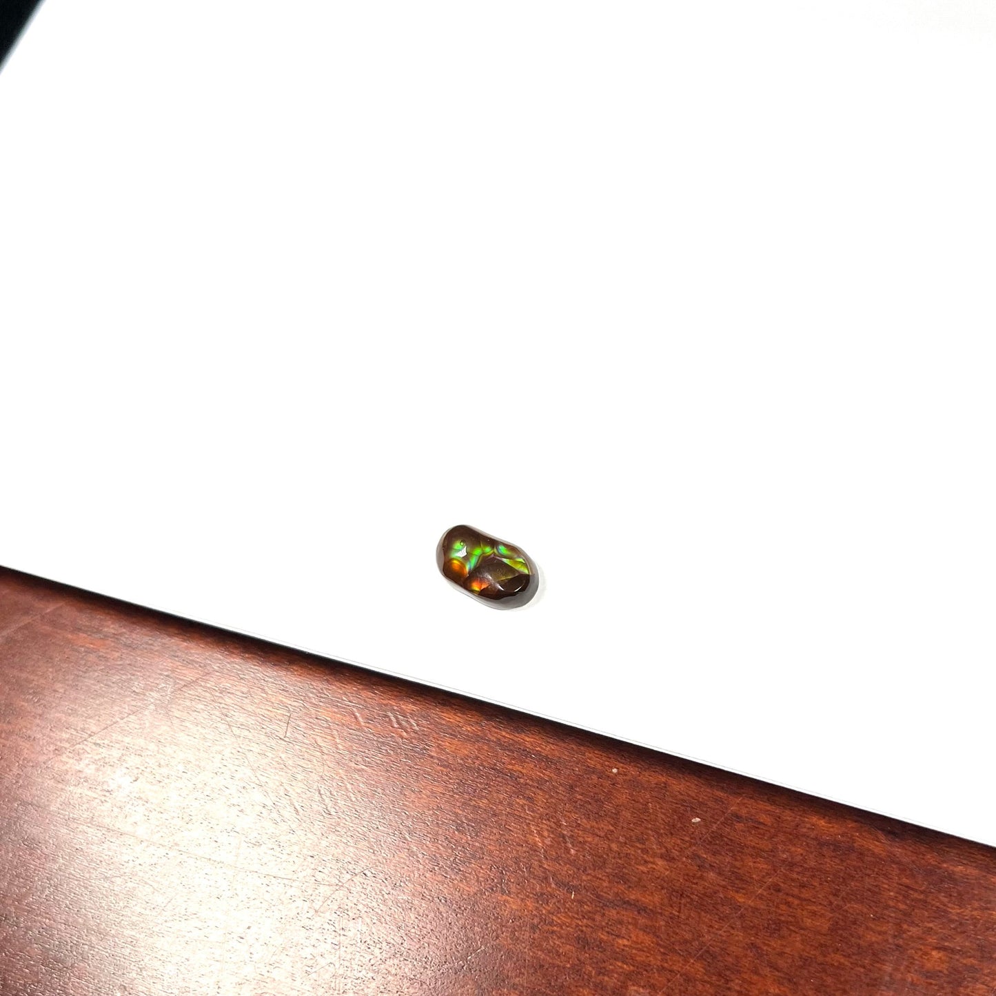 A loose, oval cabochon cut Mexican fire agate stone. The stone has multi-colored banding with blue overtones.