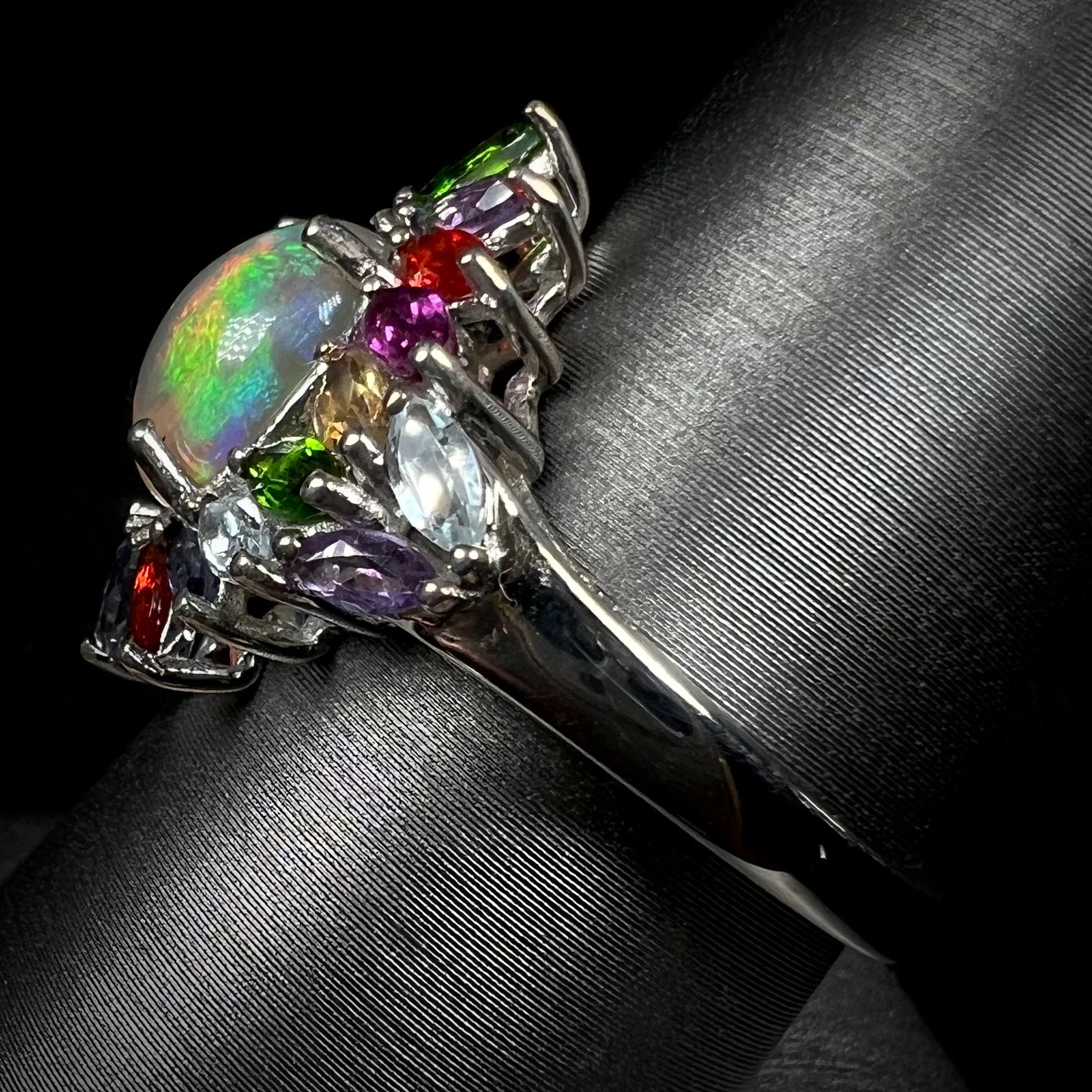 Side view of a multi-gemstone opal ring made by D'Joy. The ring's shank is in focus.