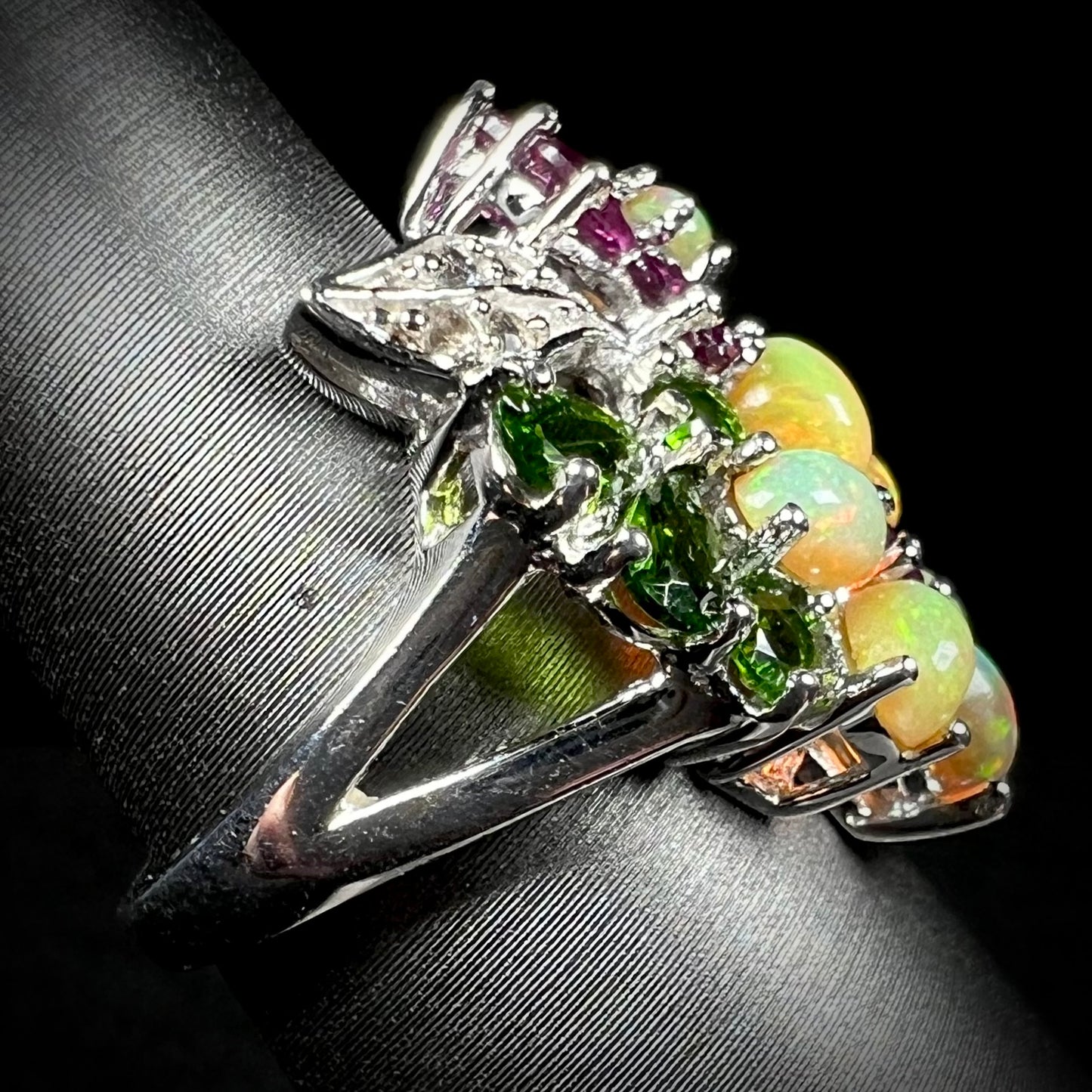 Side close-up view showing silver split shank of a multi-gemstone flower ring.