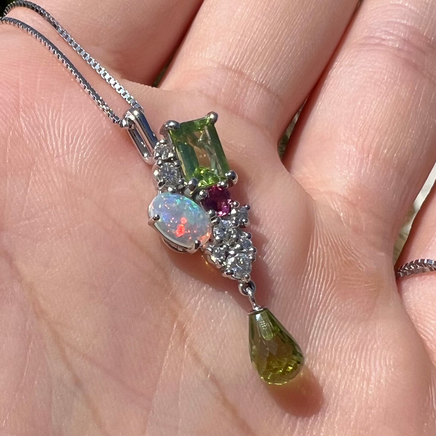 Macro angled view of a multistone cluster pendant held in the sunlight.