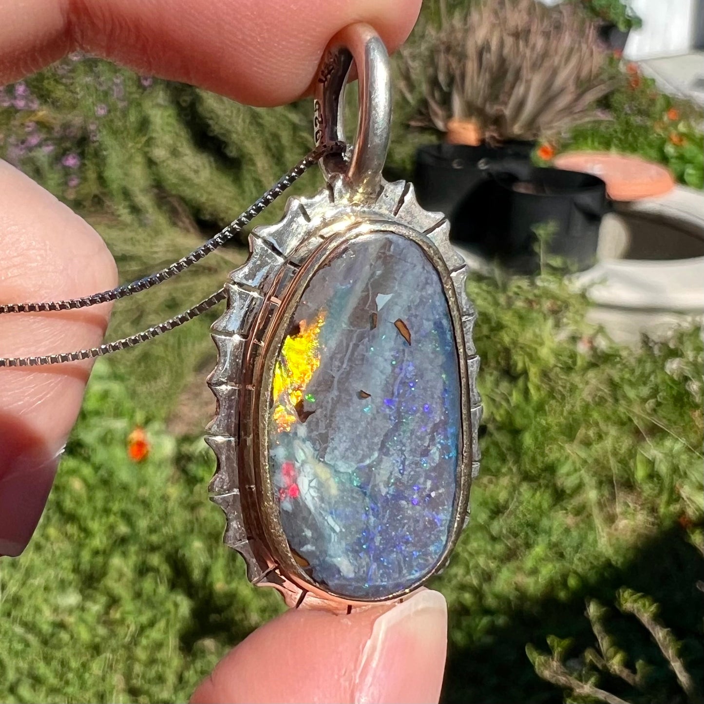A Southwest style two-tone sterling silver pendant set with a black boulder opal with a yellow gold bezel.