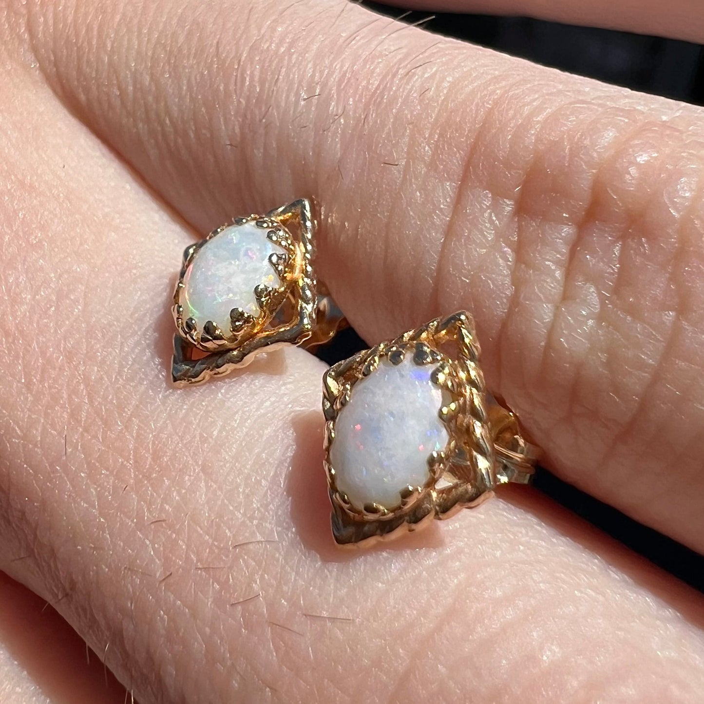 A pair of opal stud earrings. The opals are set in yellow gold diamond shaped mountings.