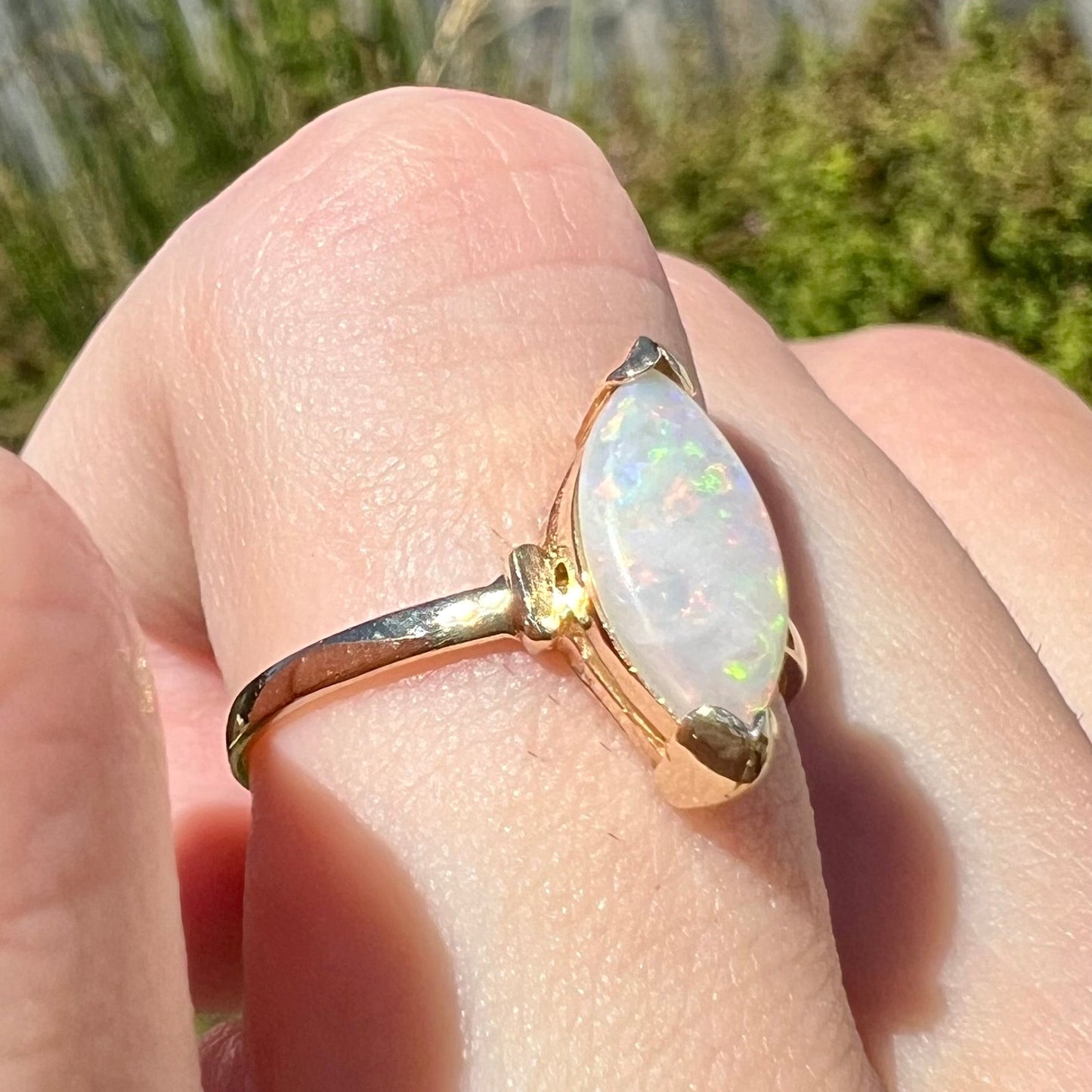 A marquise cut natural opal solitaire ring in yellow gold.