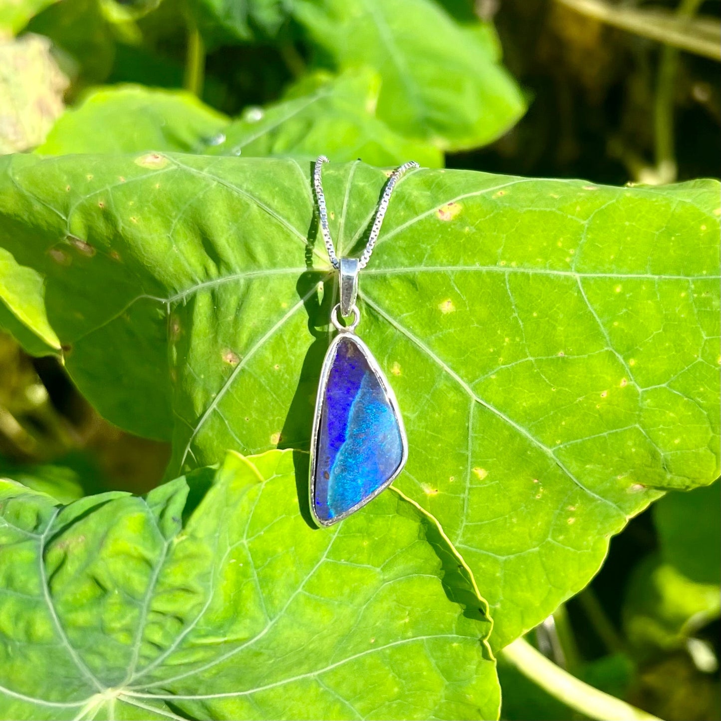 A sterling silver necklace set with a triangle shaped natural black boulder opal.