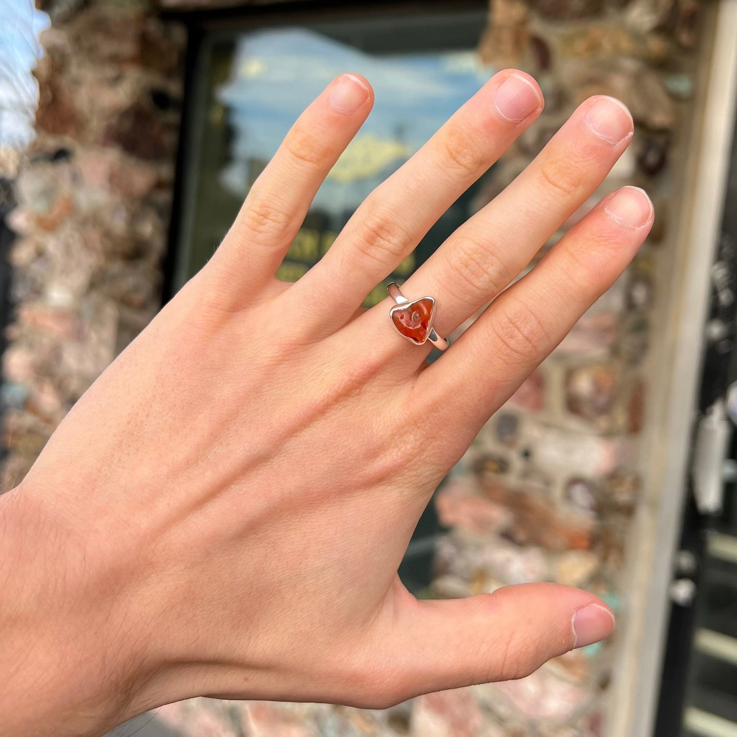 A polished fire opal crystal bezel set into a sterling silver ring. The opal is an orange color.