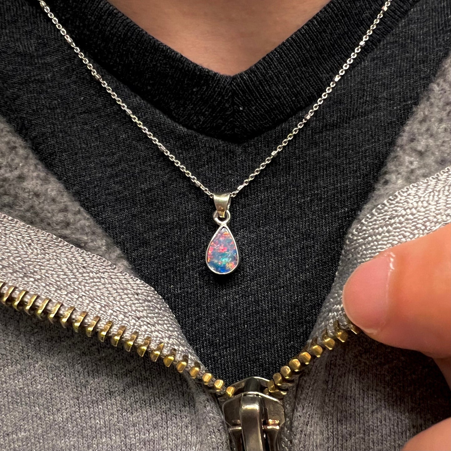 A pear shaped black opal necklace set in sterling silver. The opal vividly flashes every color of the rainbow.
