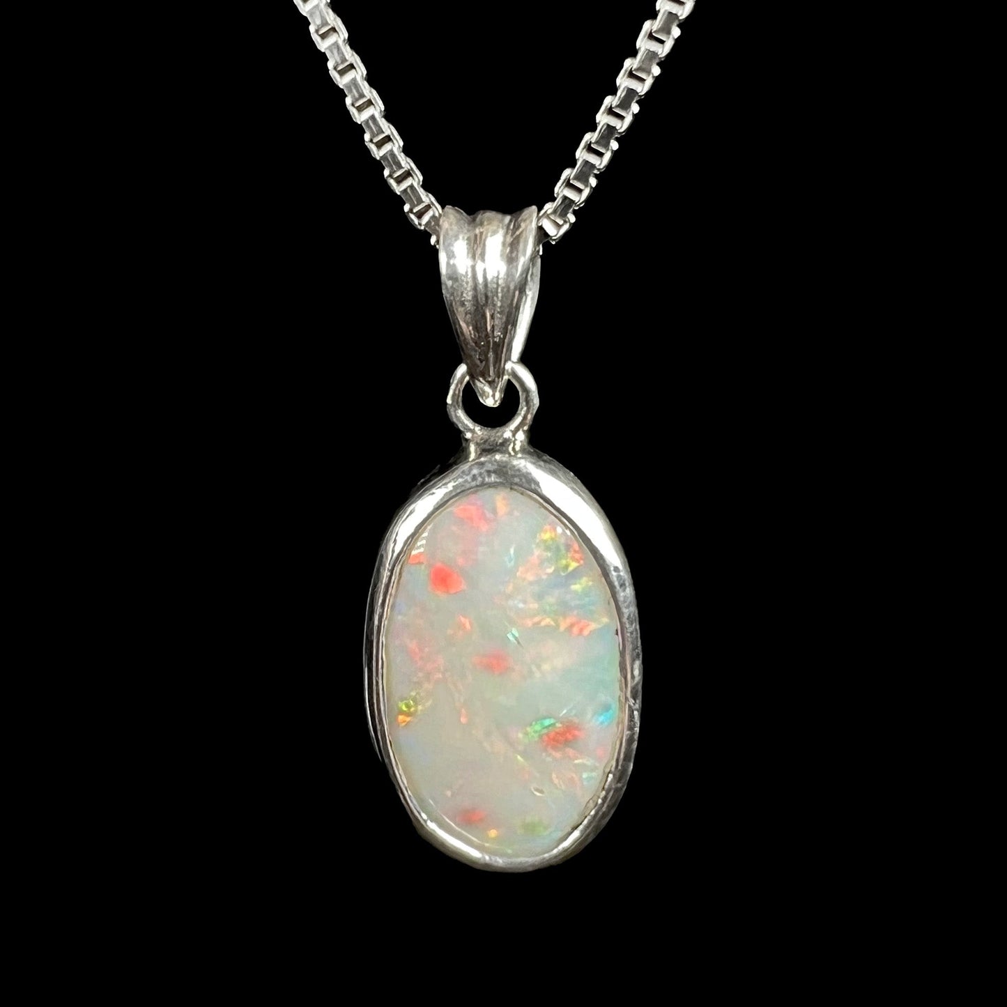 A ladies' sterling silver necklace bezel set with a natural white crystal opal. The opal has red and blue fire.