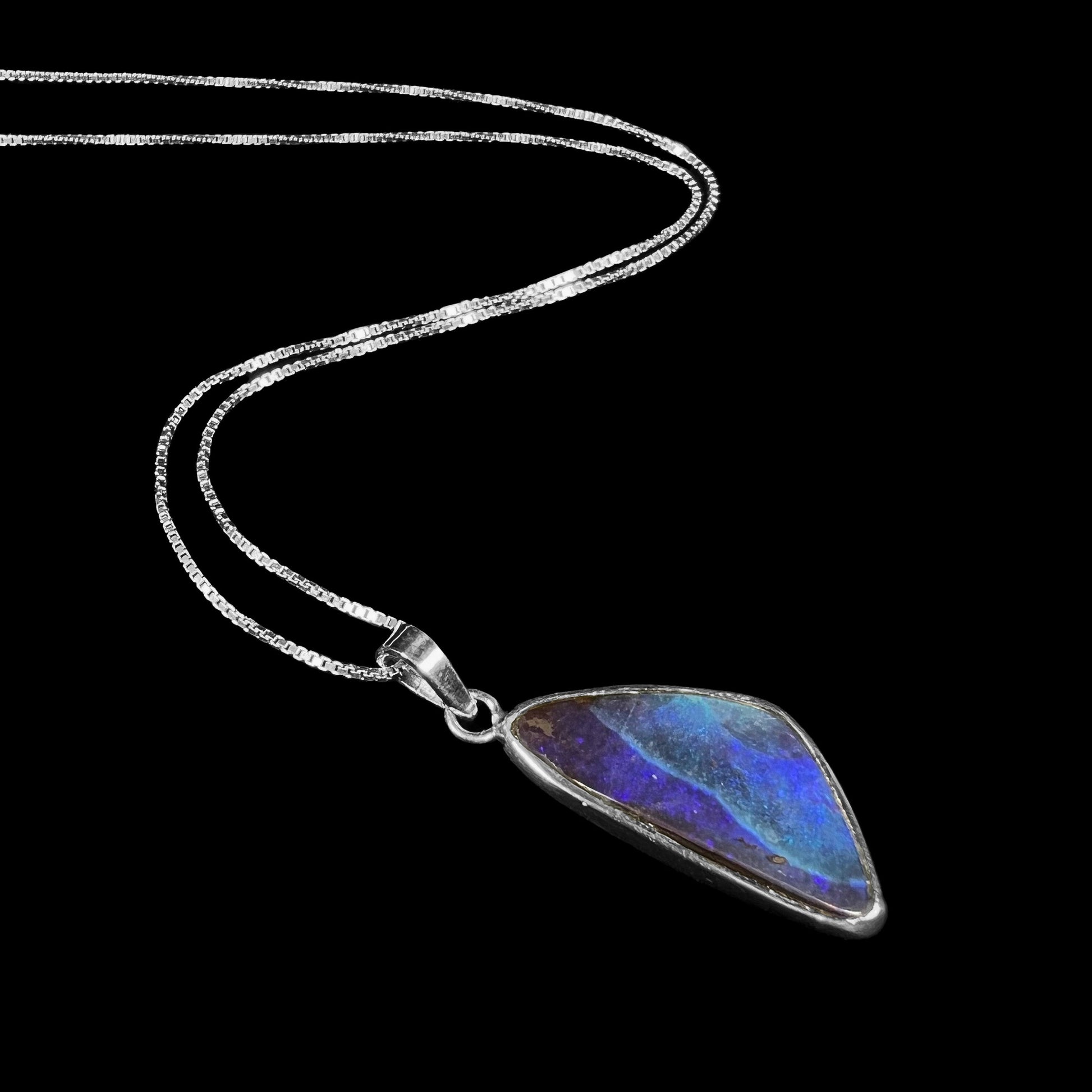 A ladies' sterling silver necklace bezel set with a triangle drop shaped Australian black boulder opal.