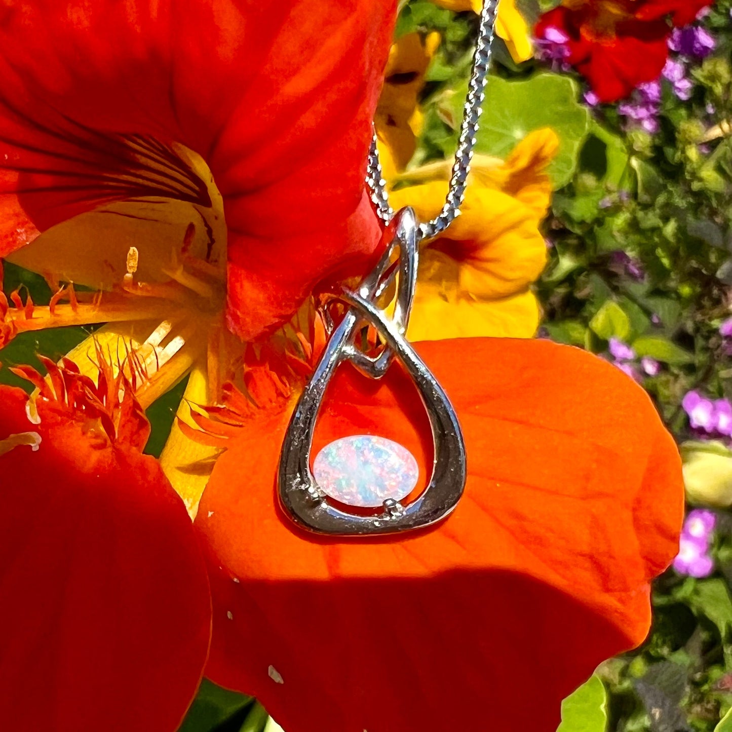 A ladies' sterling silver pendant set with an oval cabochon cut natural white crystal opal.