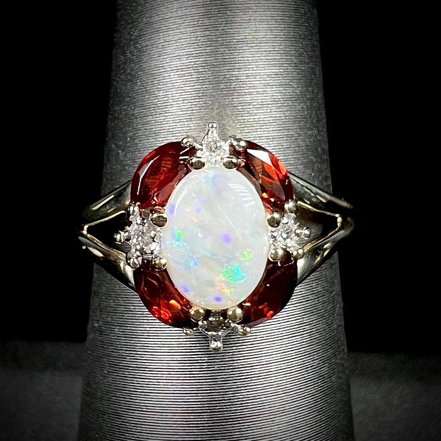 A ladies natural opal ring in yellow gold. The opal is surrounded by red marquise cut garnets and diamonds.