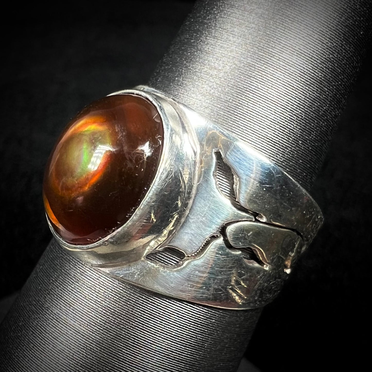A silver fire agate ring with a nature-inspired open vine and flower design along the band, shown at an angle.