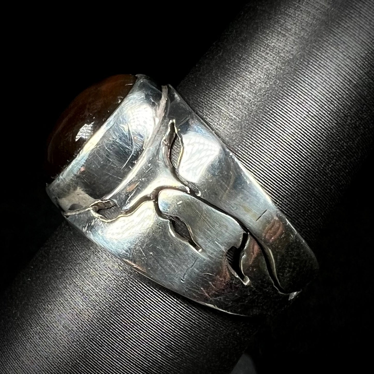 A sterling silver ring with an open nature-inspired vine motif in the design, shown from the side.