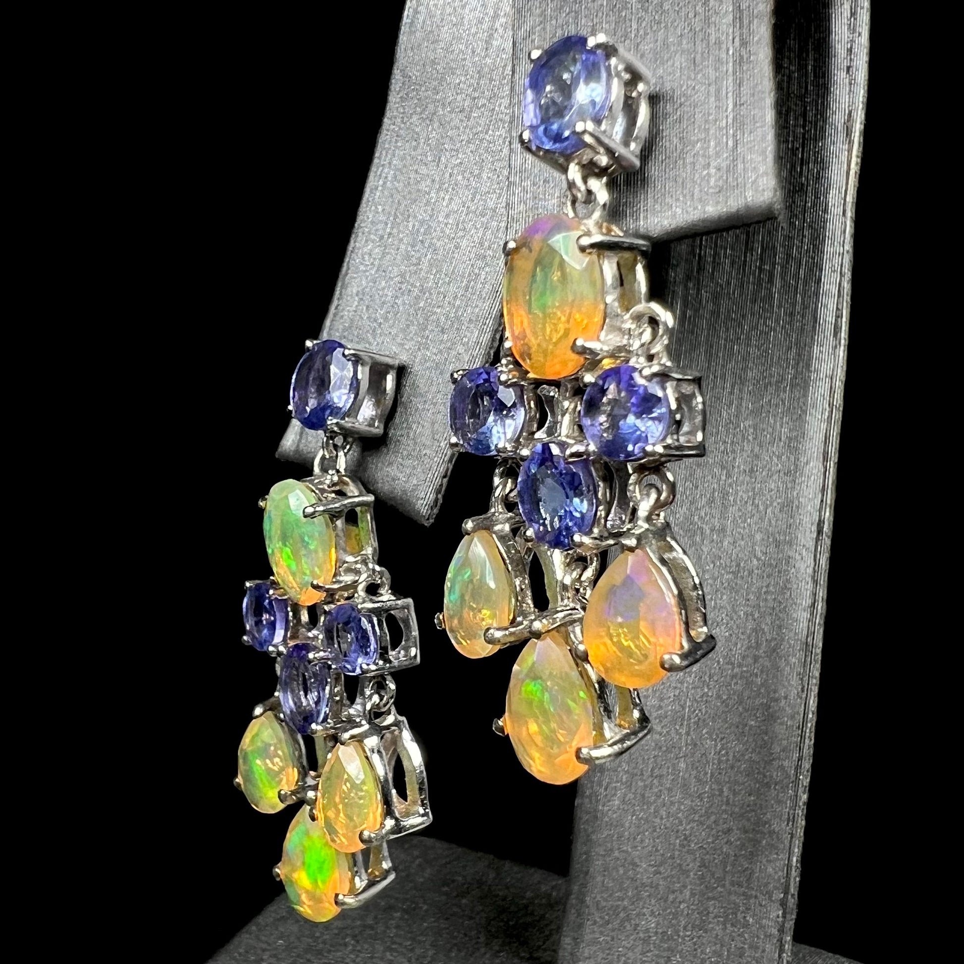 A pair of dangling sterling silver Ethiopian opal and tanzanite chandelier earrings, shown at an angle.