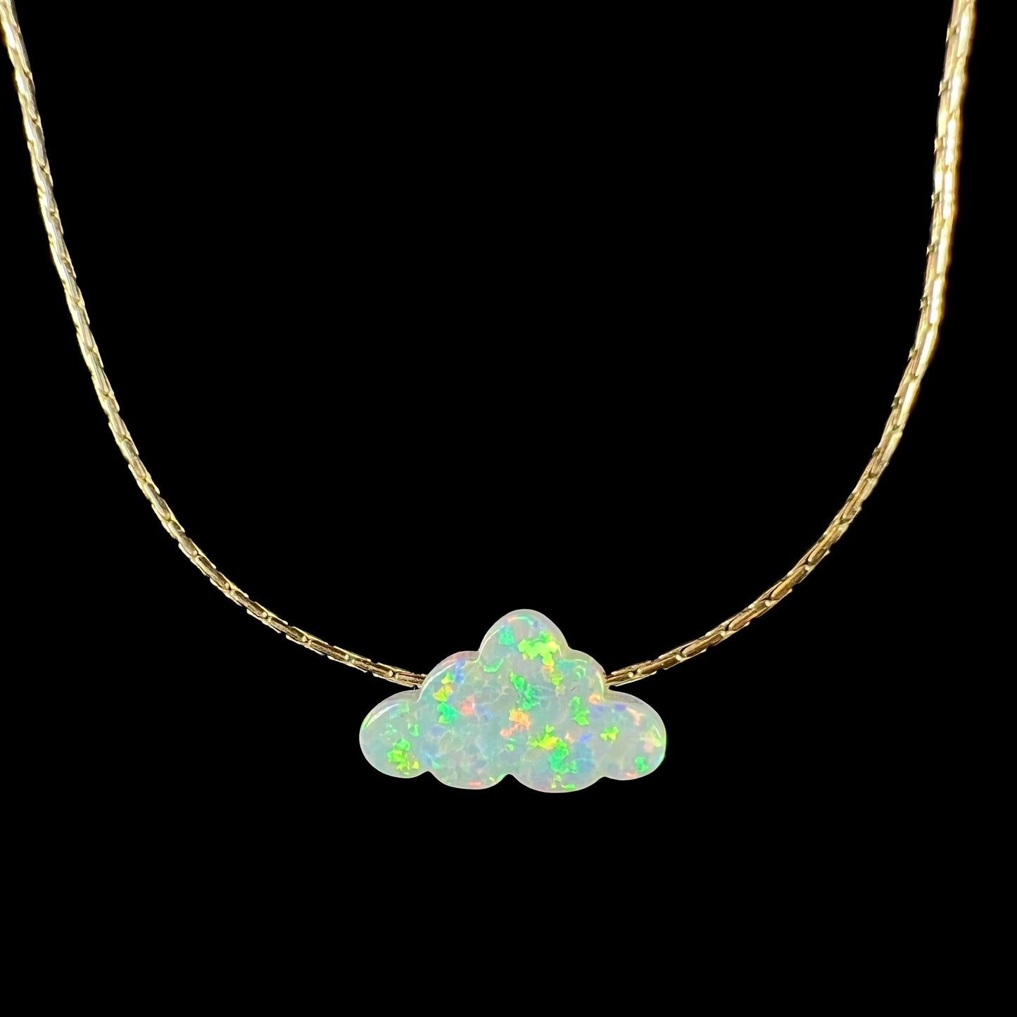 Synthetic opal cloud necklace shown from the back against black backdrop.