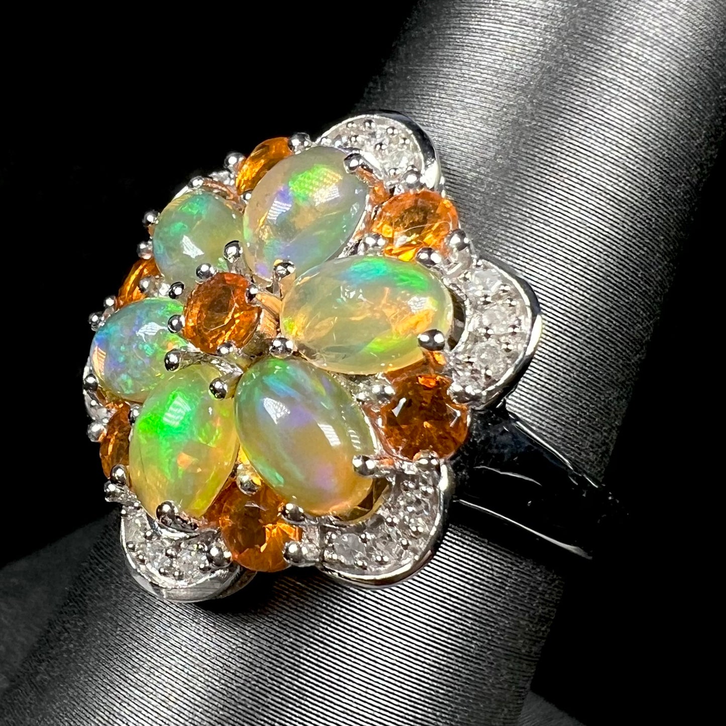 Angled view of a silver opal cluster flower ring set with diamond accents.