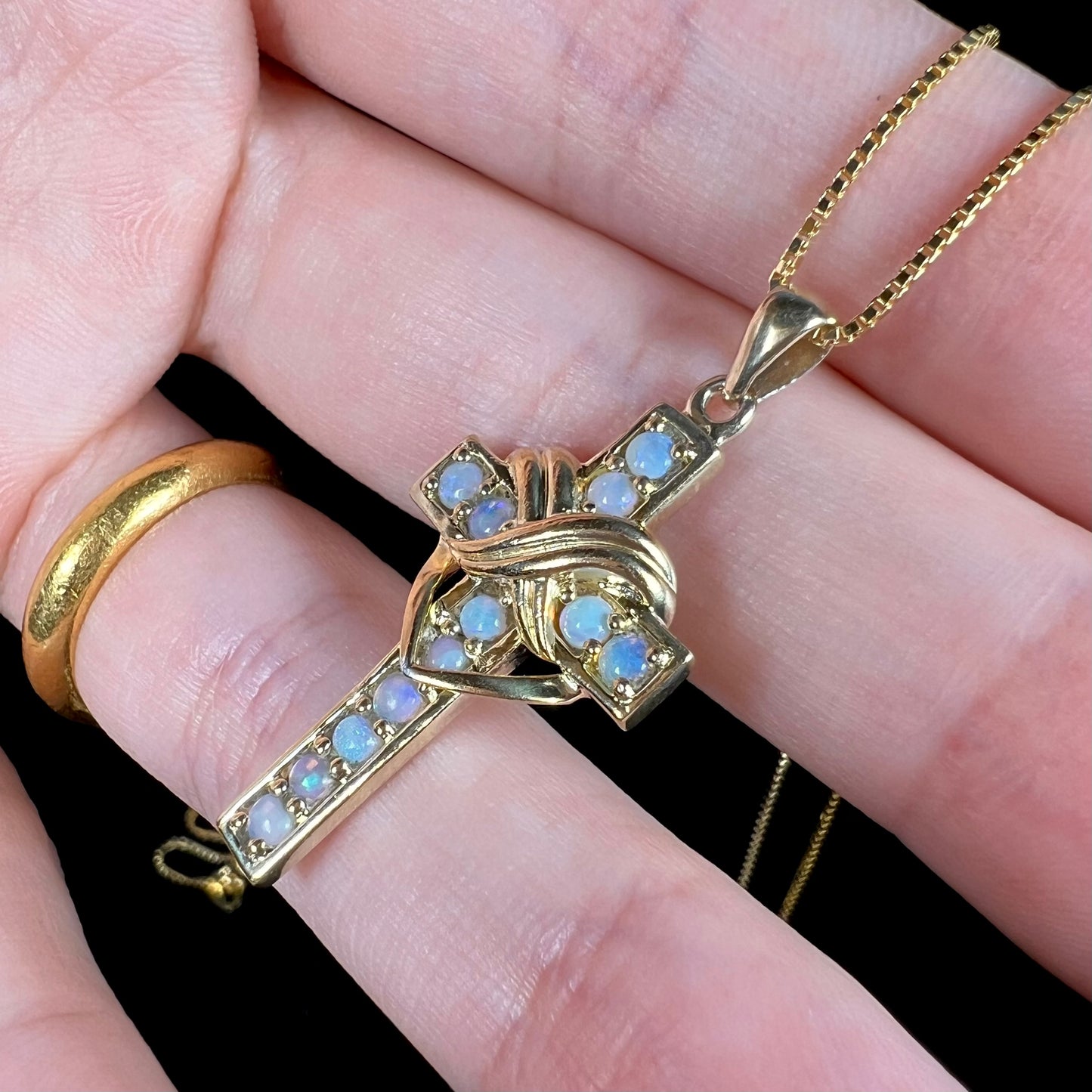 Opposite side angled view of opal cross necklace showing detail.