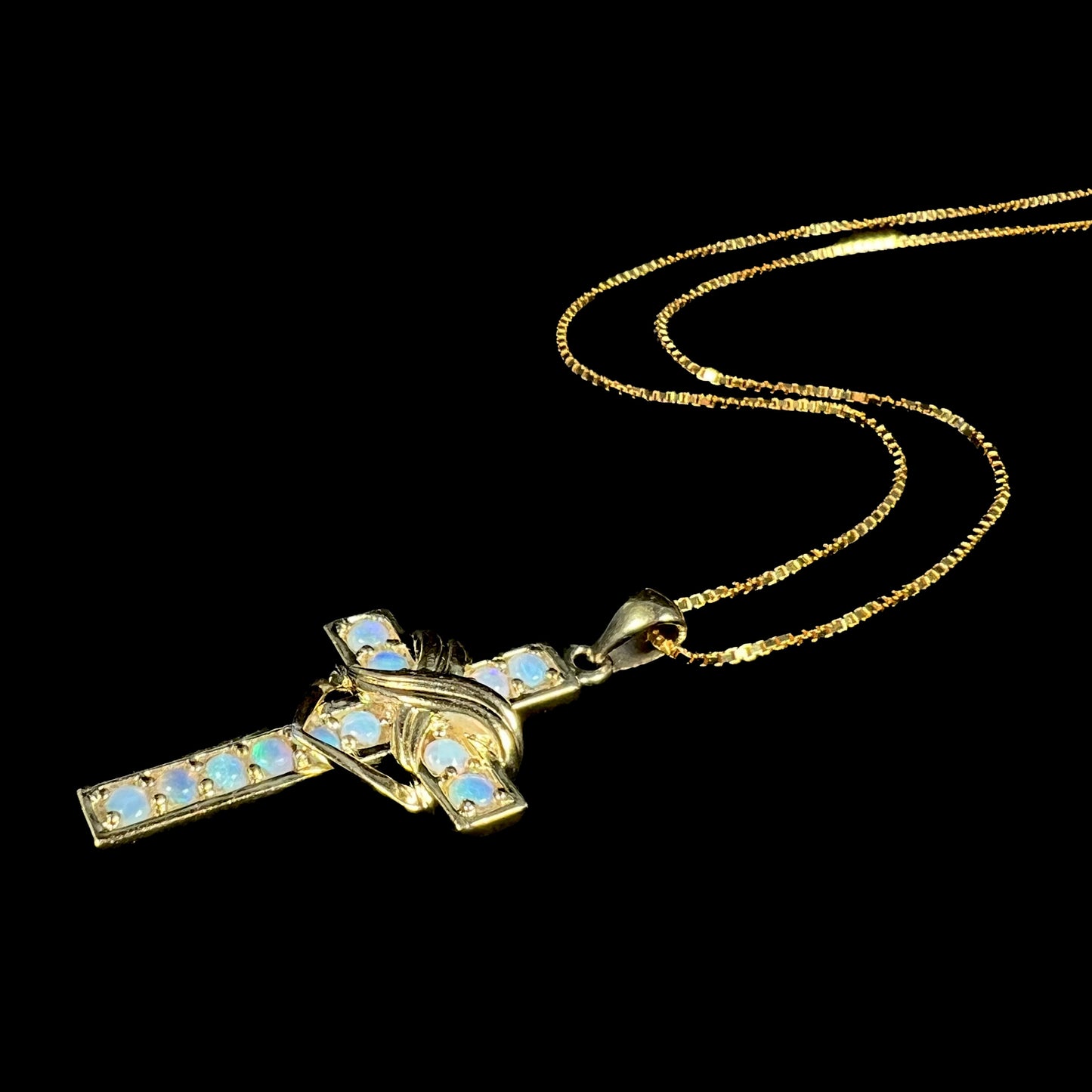 Angled view of opal cross necklace with subtle green and blue color play.