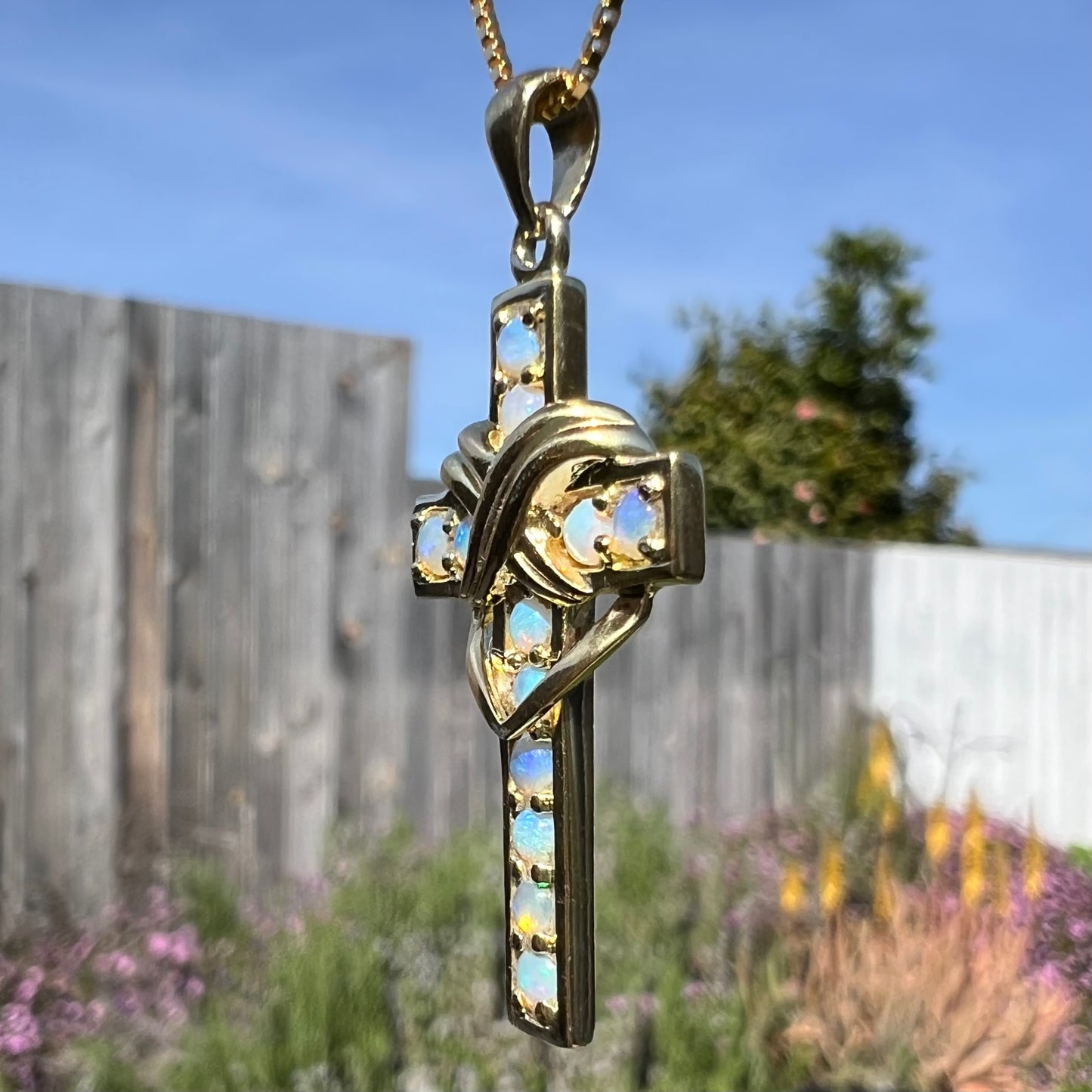 Opposite side angled view of cross necklace in sunlight.