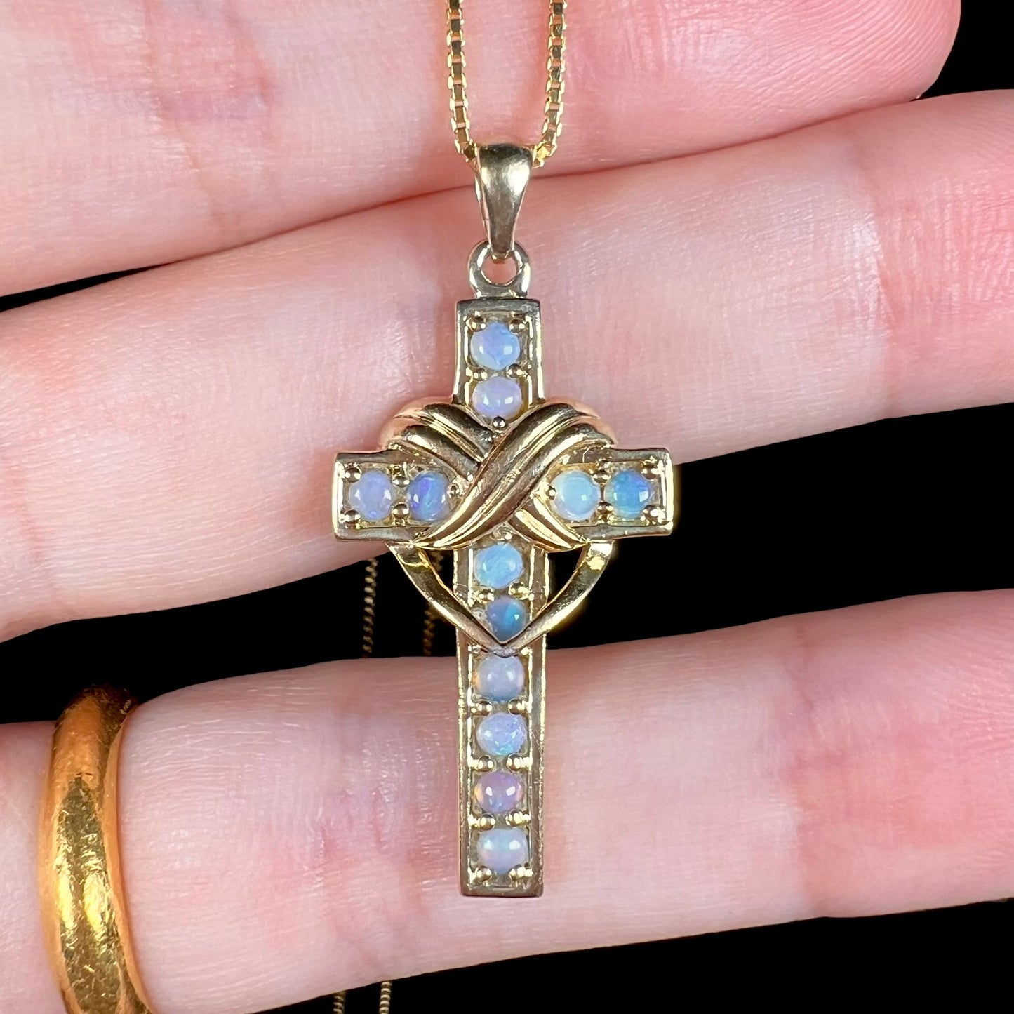 Macro view of opal cross necklace showing faint bluish tint in stones.