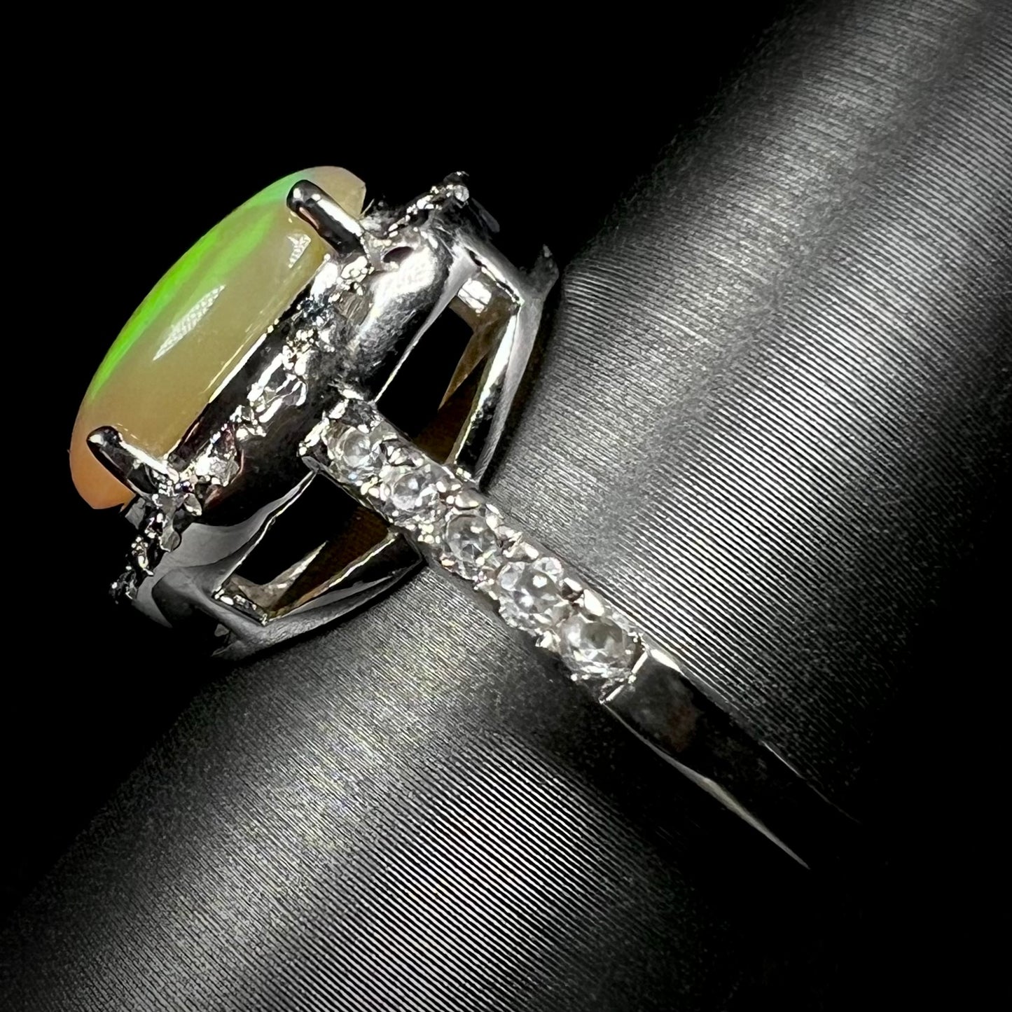 Side profile view of a sterling silver Ethiopian fire opal ring with a CZ halo.
