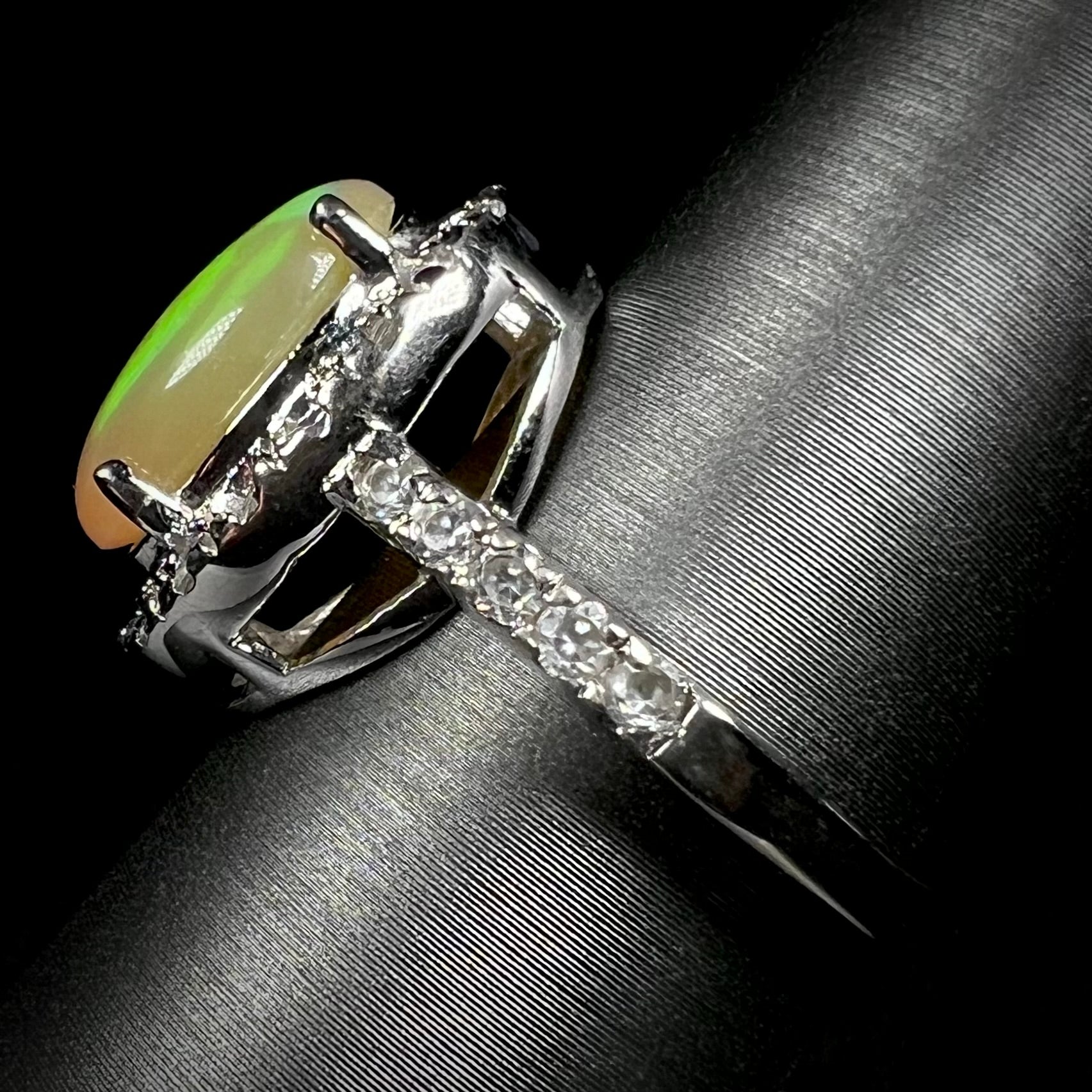 Side profile view of a sterling silver Ethiopian fire opal ring with a CZ halo.