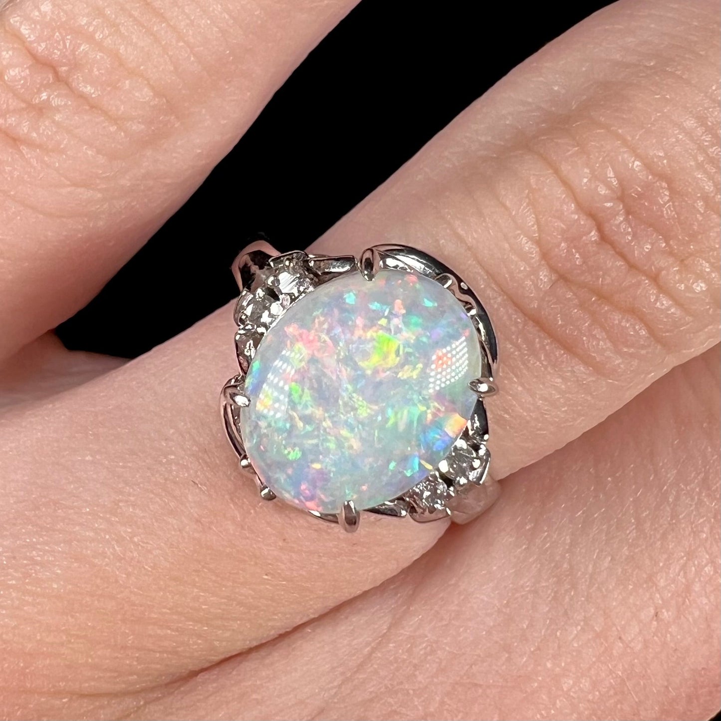 A platinum and diamond ring prong-set with an Australian opal. The opal has pink color play.