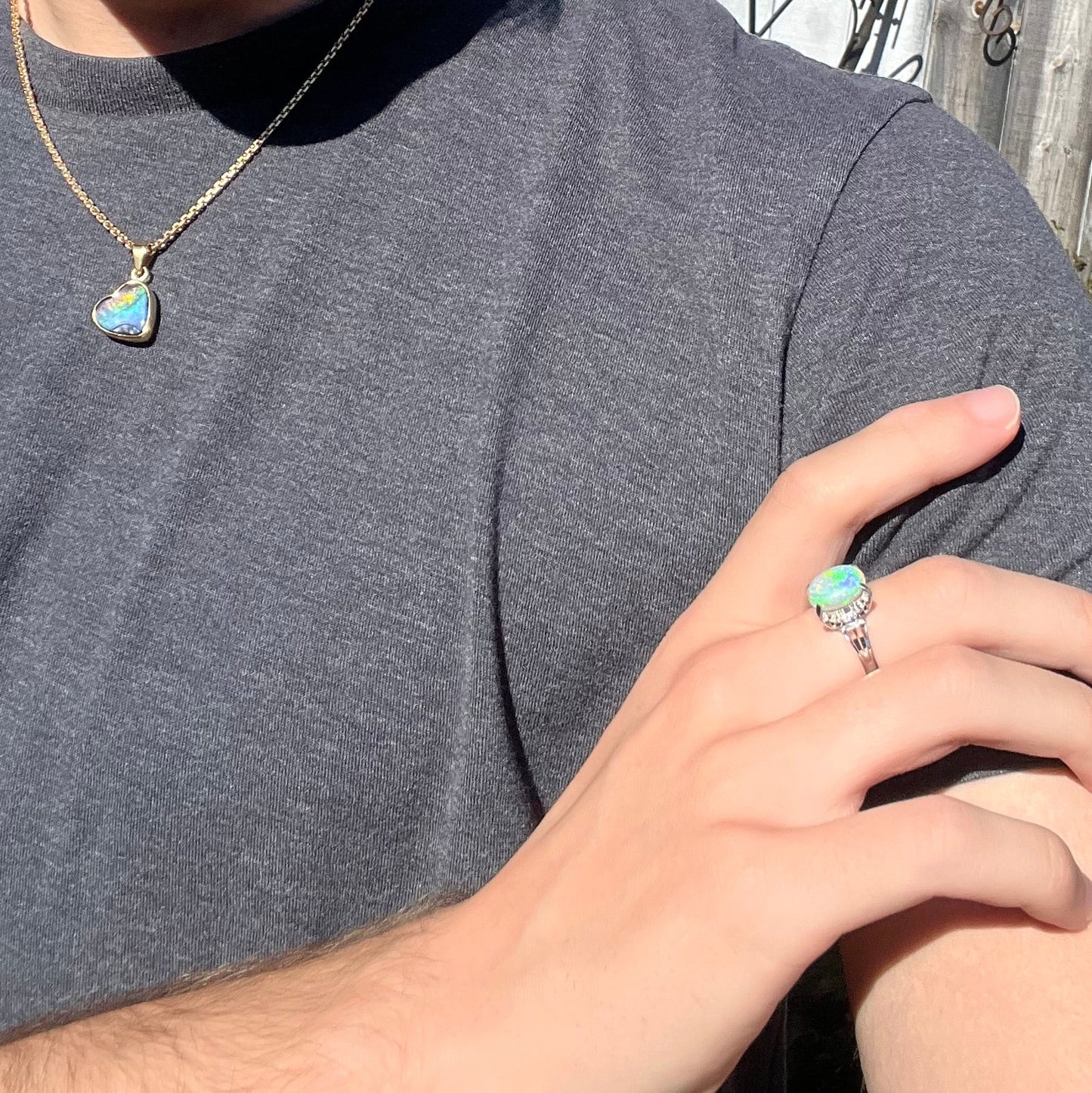A platinum filigree opal engagement ring set with diamond accents. The opal has green-blue colors.