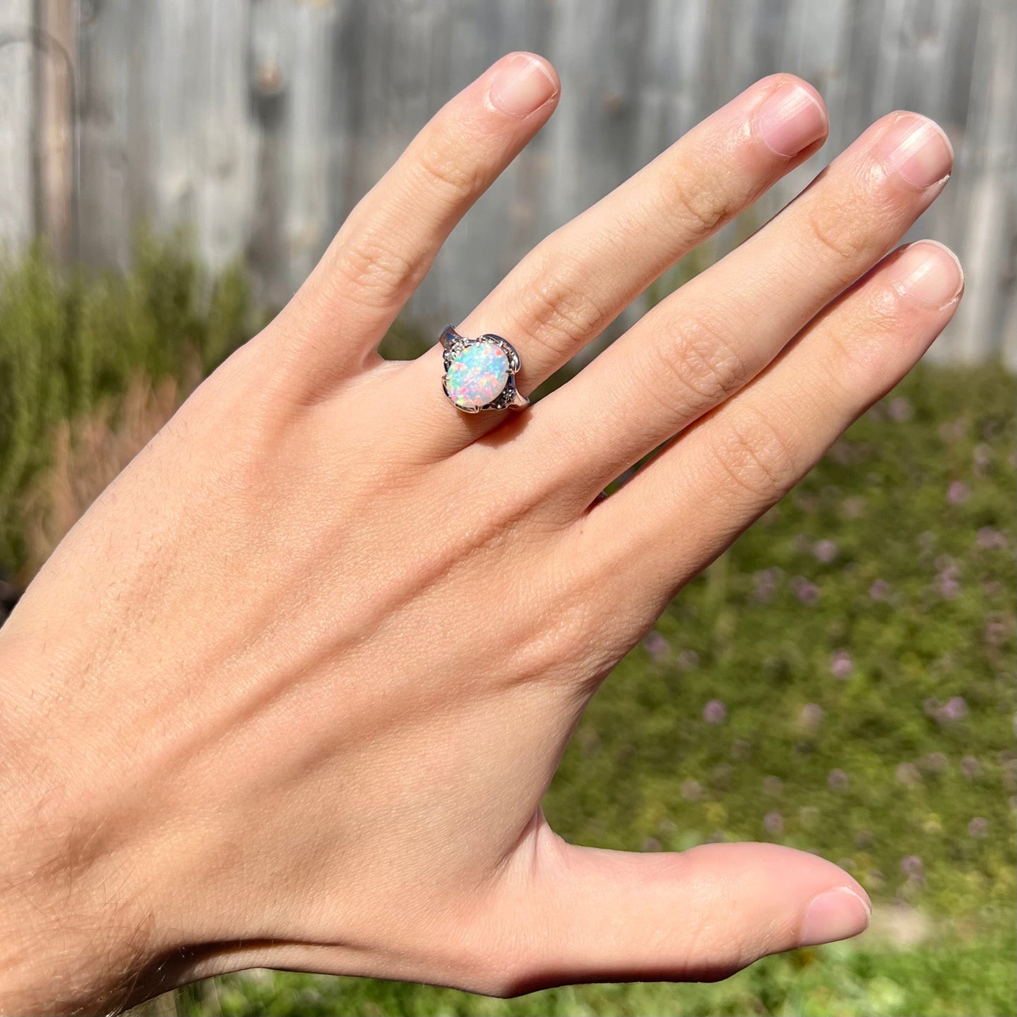 A platinum and diamond ring prong-set with an Australian opal. The opal has pink color play.