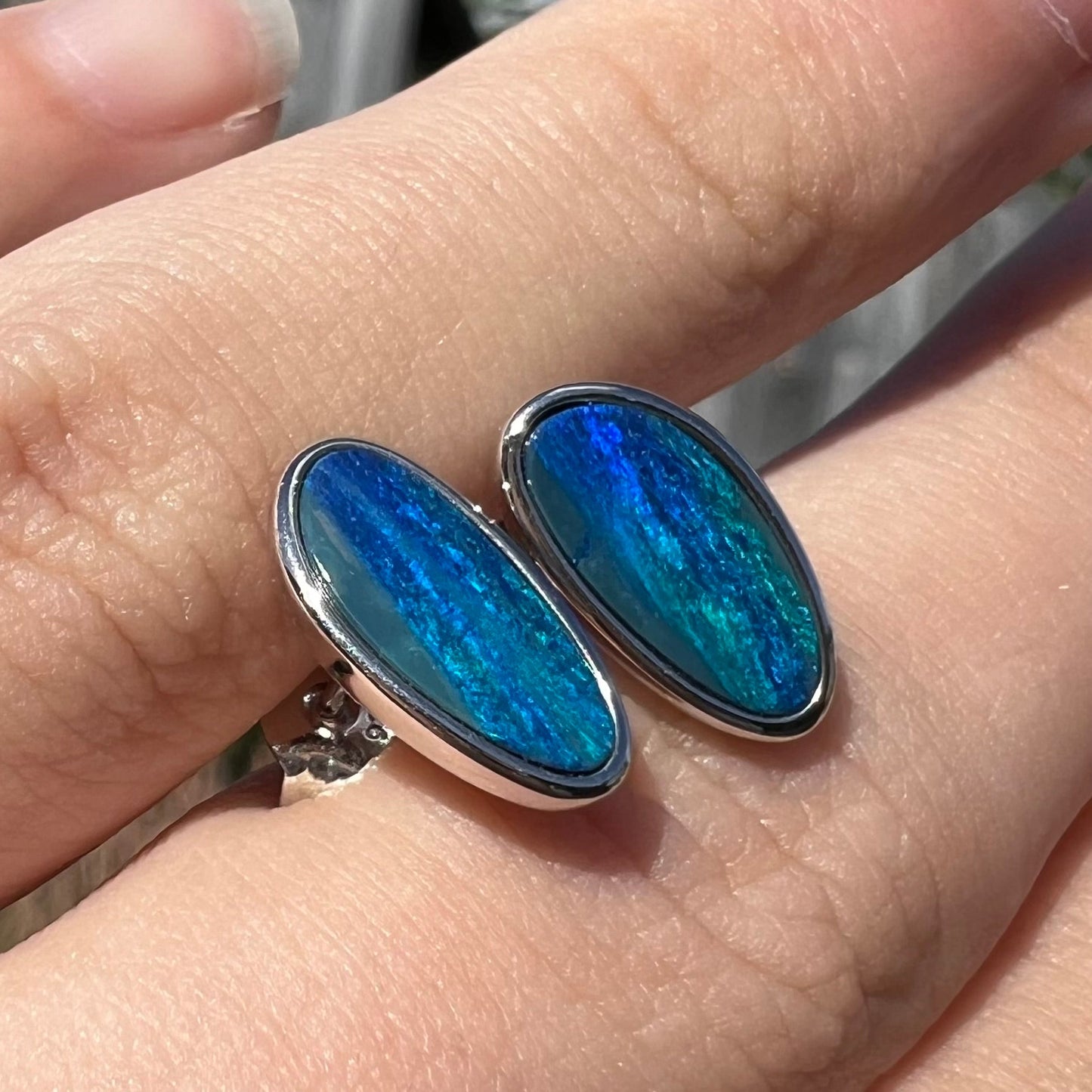 A pair of sterling silver opal doublet stud earrings. The opals have a vivid blue color.