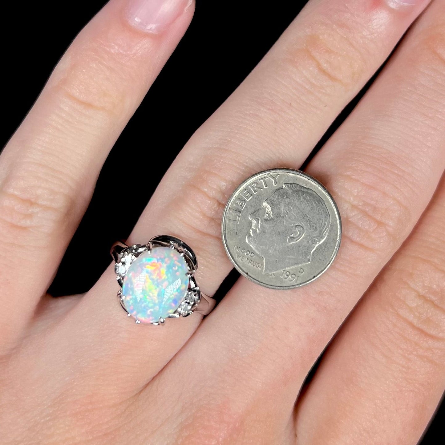 A platinum and diamond ring prong-set with an Australian opal. The opal has pink color play.