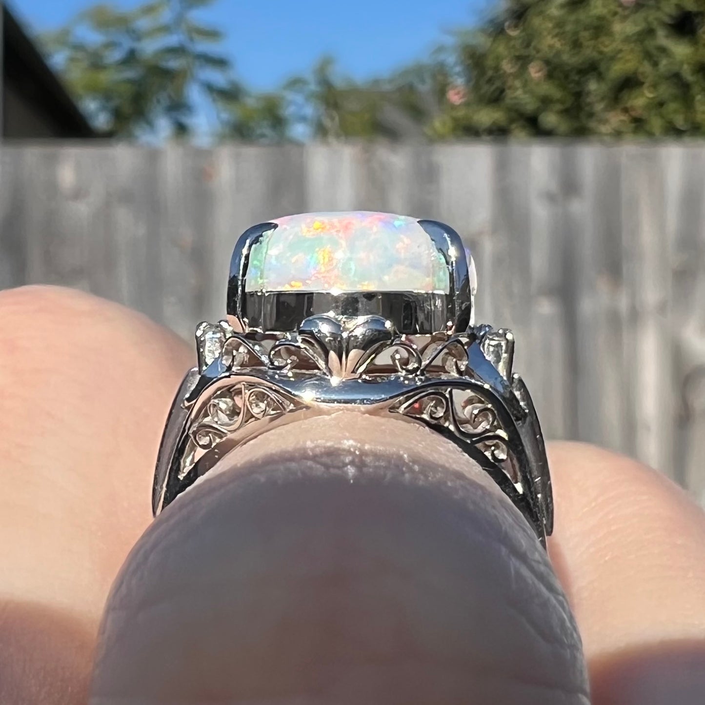The gallery view of a platinum opal and diamond engagement ring. This angle showcases the ring's filigree design.