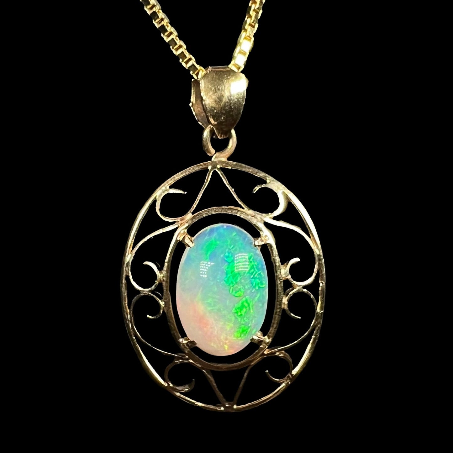 An 18 karat yellow gold filigree opal necklace. The opal has bright green color play.