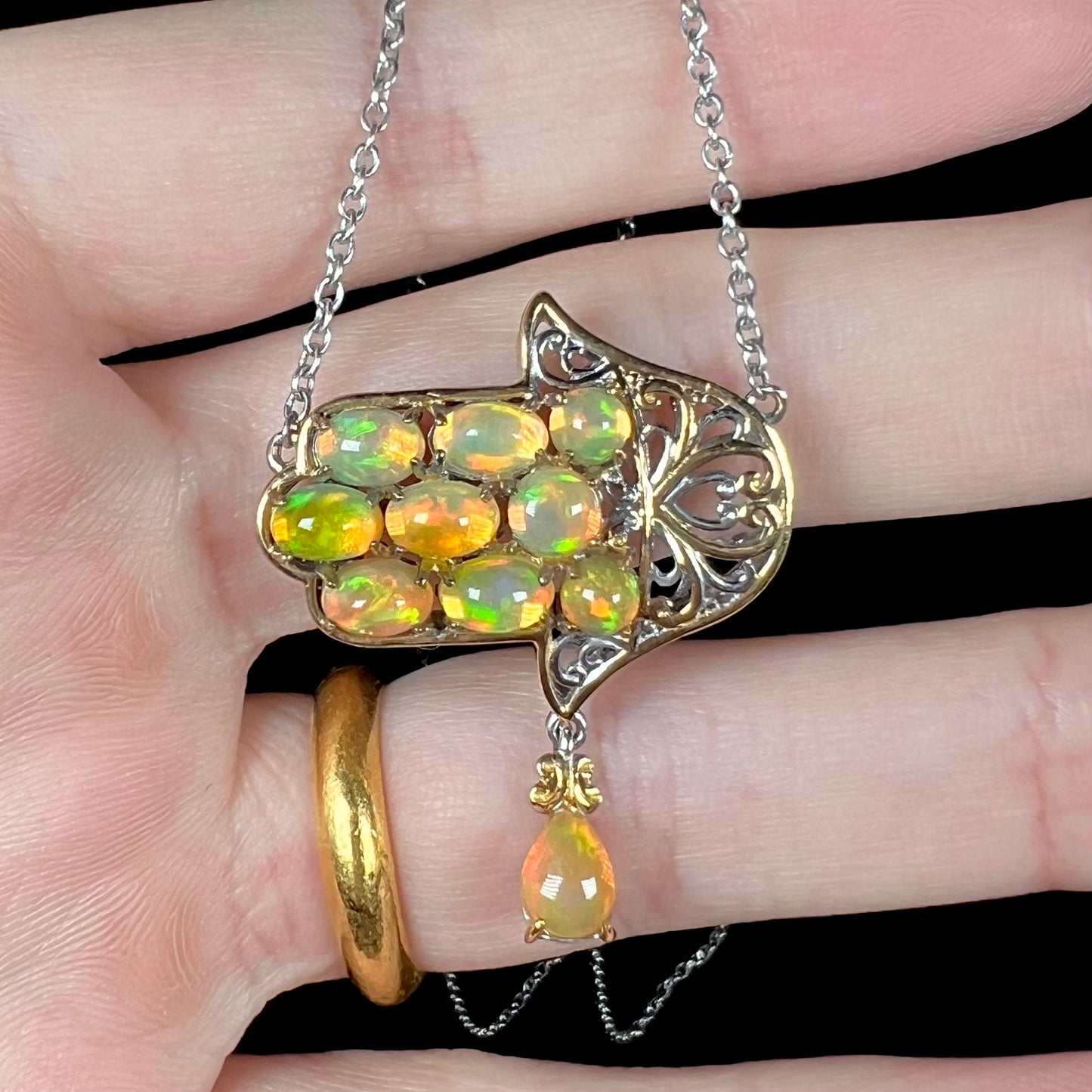An opal hand necklace, referred to as the hamsa, shown close-up from the front.