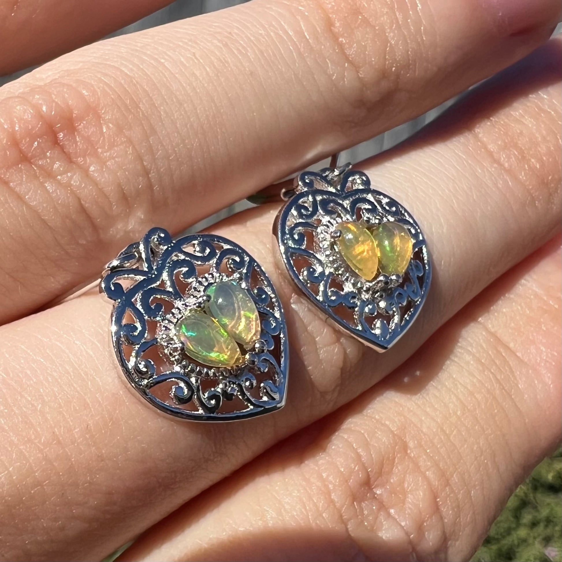 A pair of dangling sterling silver filigree heart earrings, each set with two Ethiopian opals.