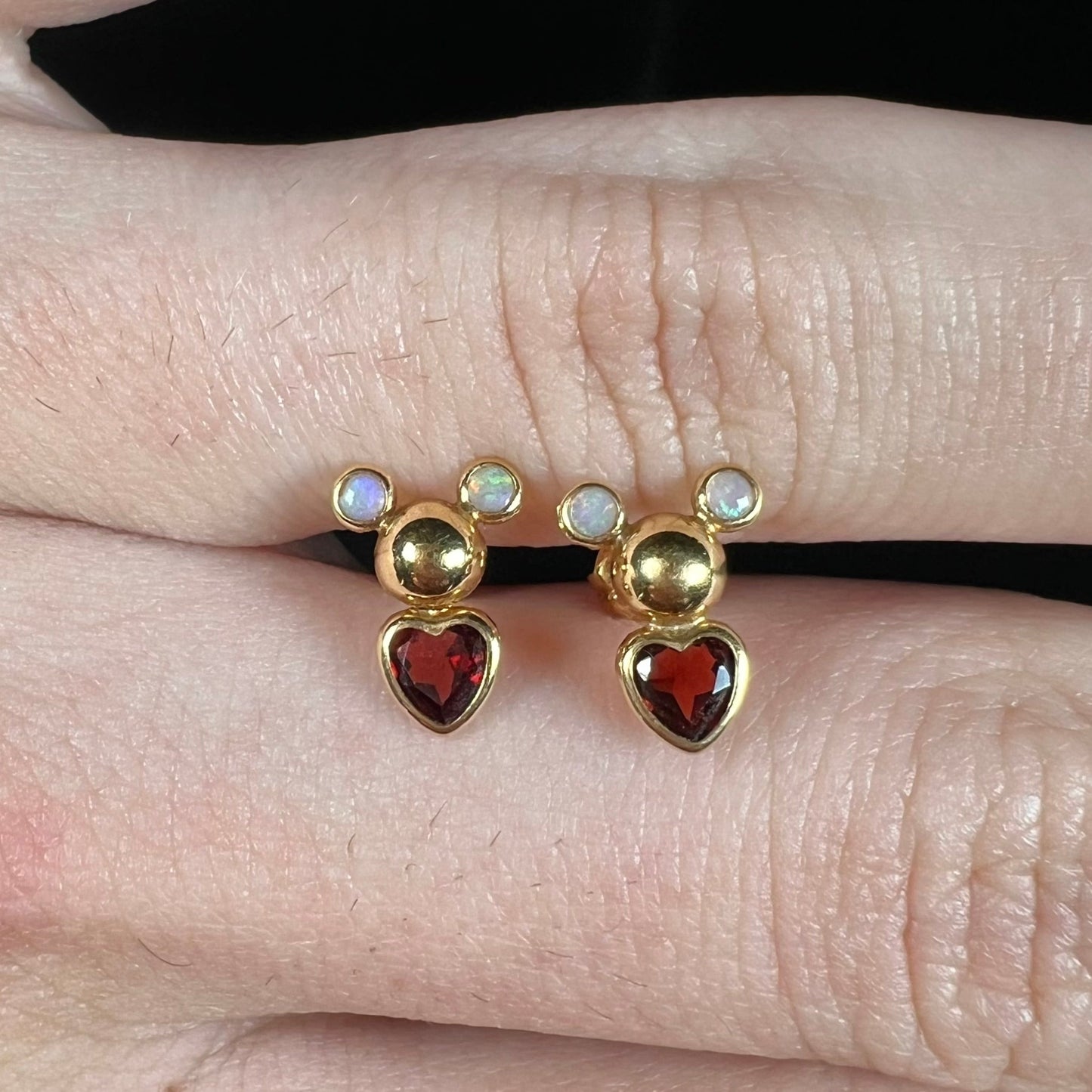 A pair of 18 karat yellow gold stud earrings set with two round fire opals and heart shaped garnets.
