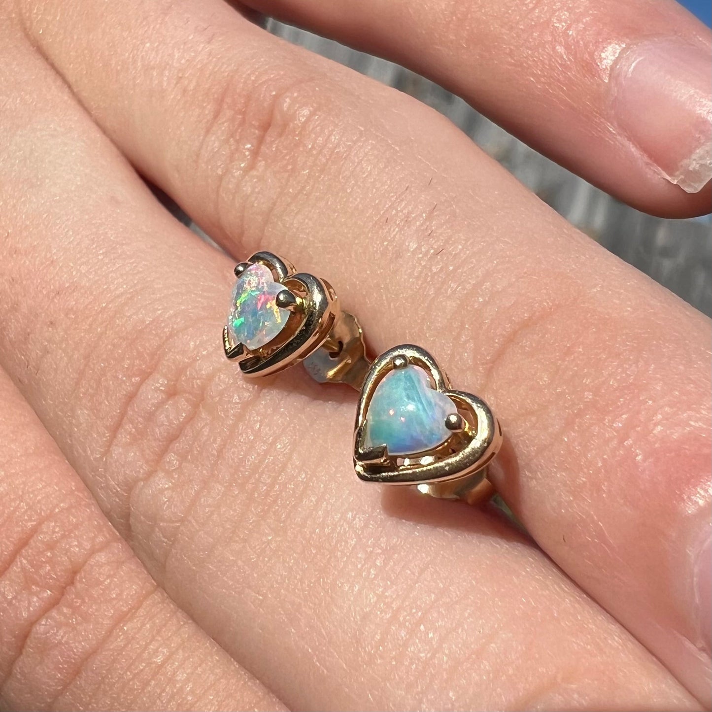 Yellow gold natural opal heart stud earrings. The earrings have bright red and blue colors.