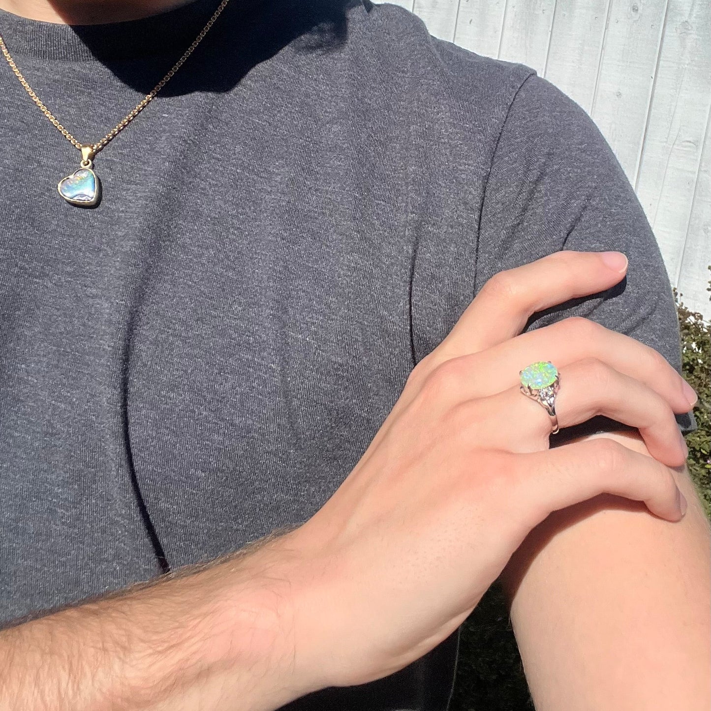 An Australian crystal opal and diamond engagement ring set in a platinum filigree mounting. The opal plays green/blue colors and has a crack.