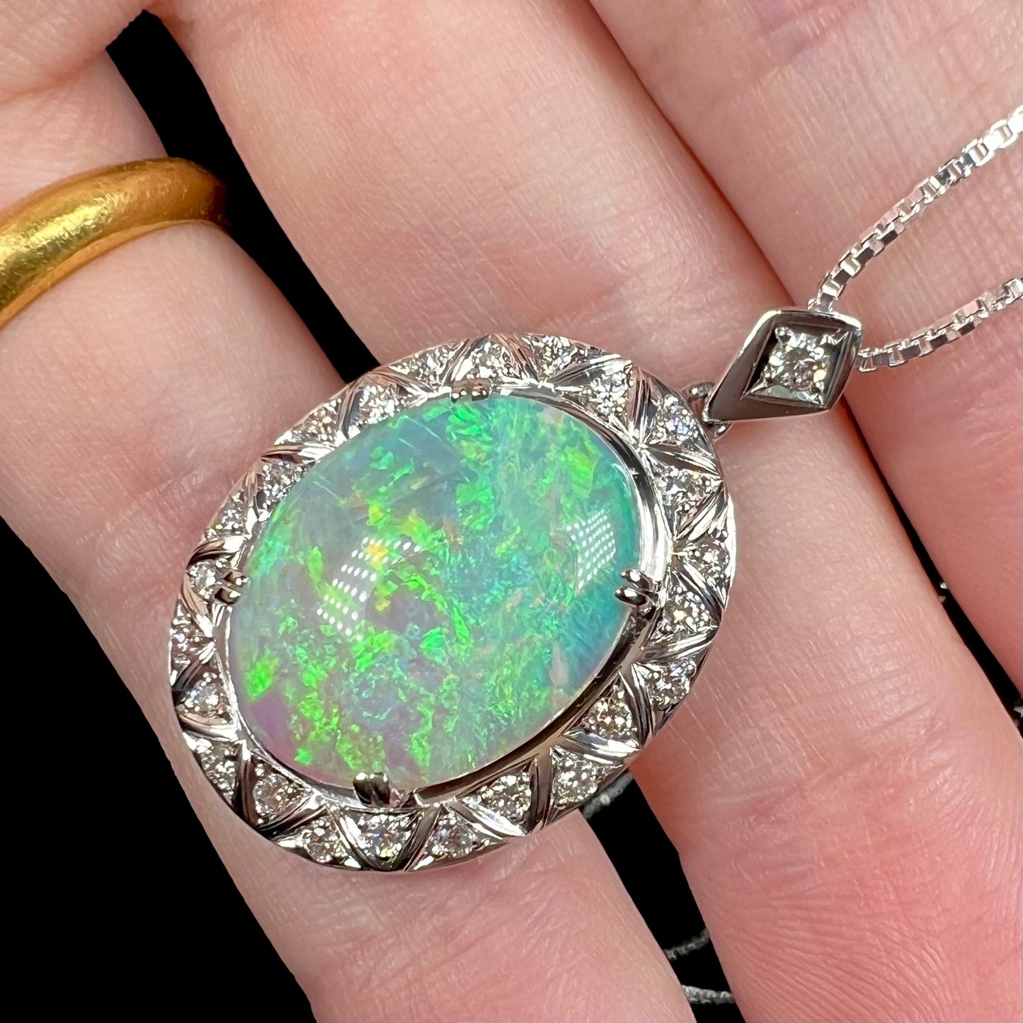 Side view of platinum opal pendant showing subtler green flashes on the opposite side.