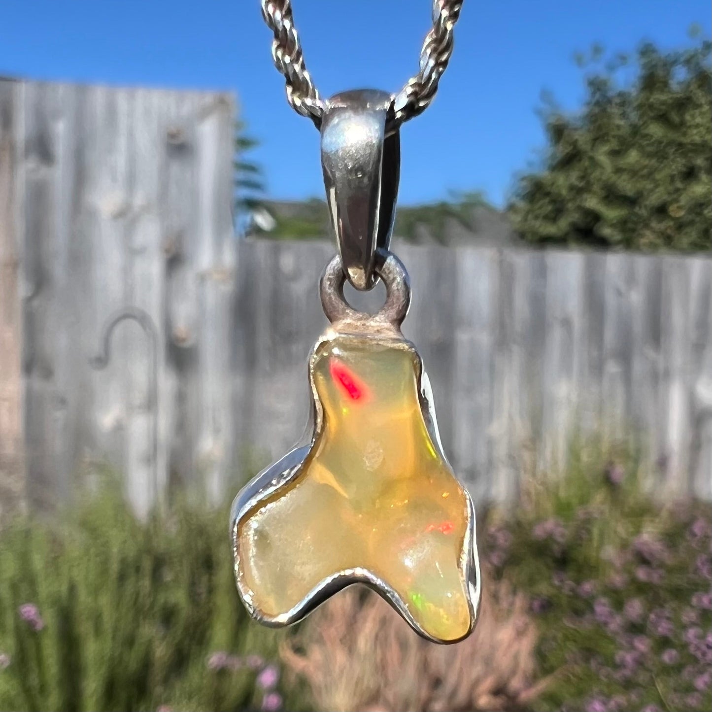 A freeform shaped Mexican fire opal necklace on a sterling silver rope chain.