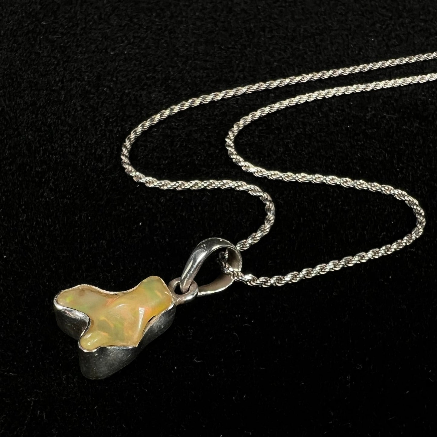 A freeform shaped Mexican fire opal necklace on a sterling silver rope chain.