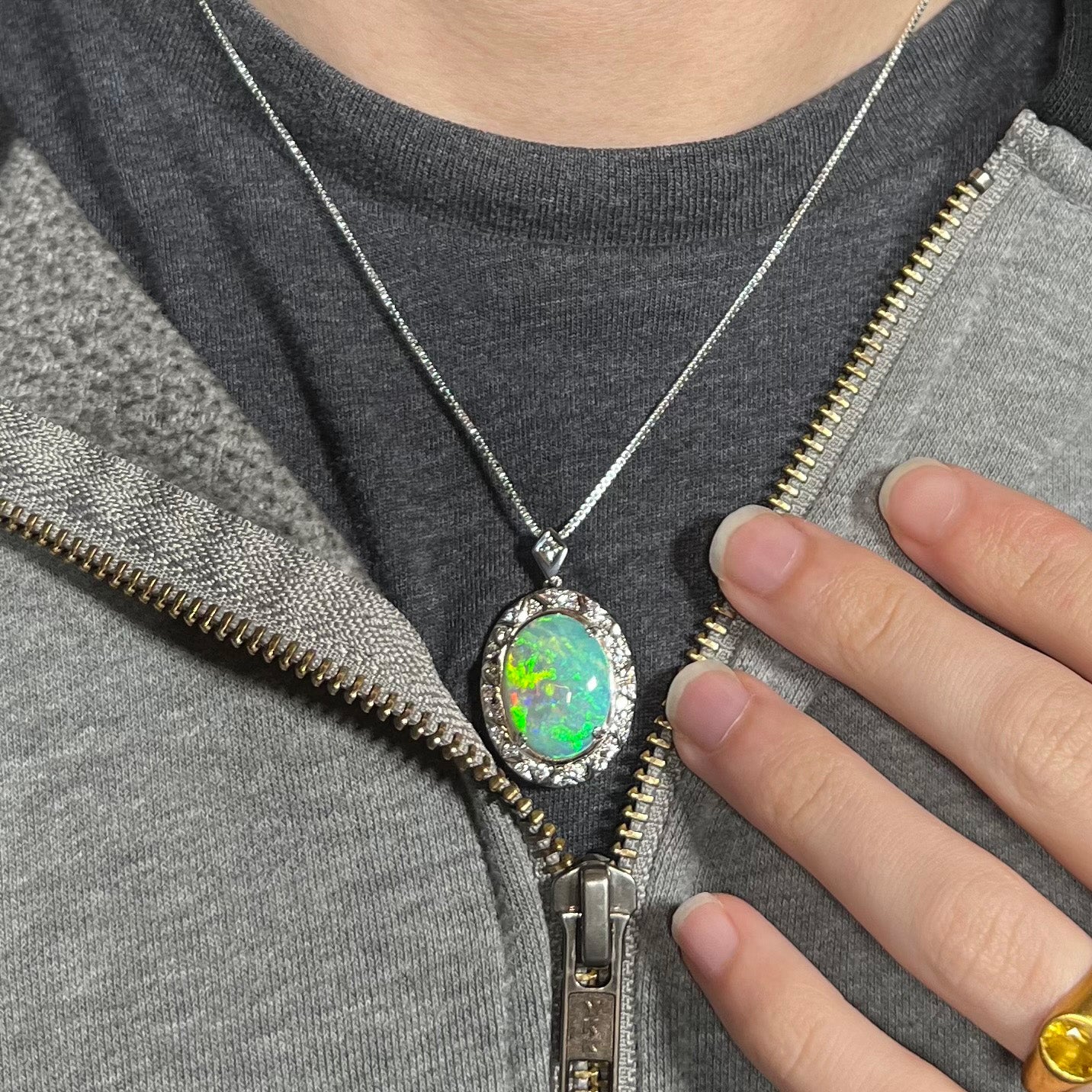 Crystal opal necklace worn over a black t-shirt with zip-up sweatshirt, showing green and red flashes.