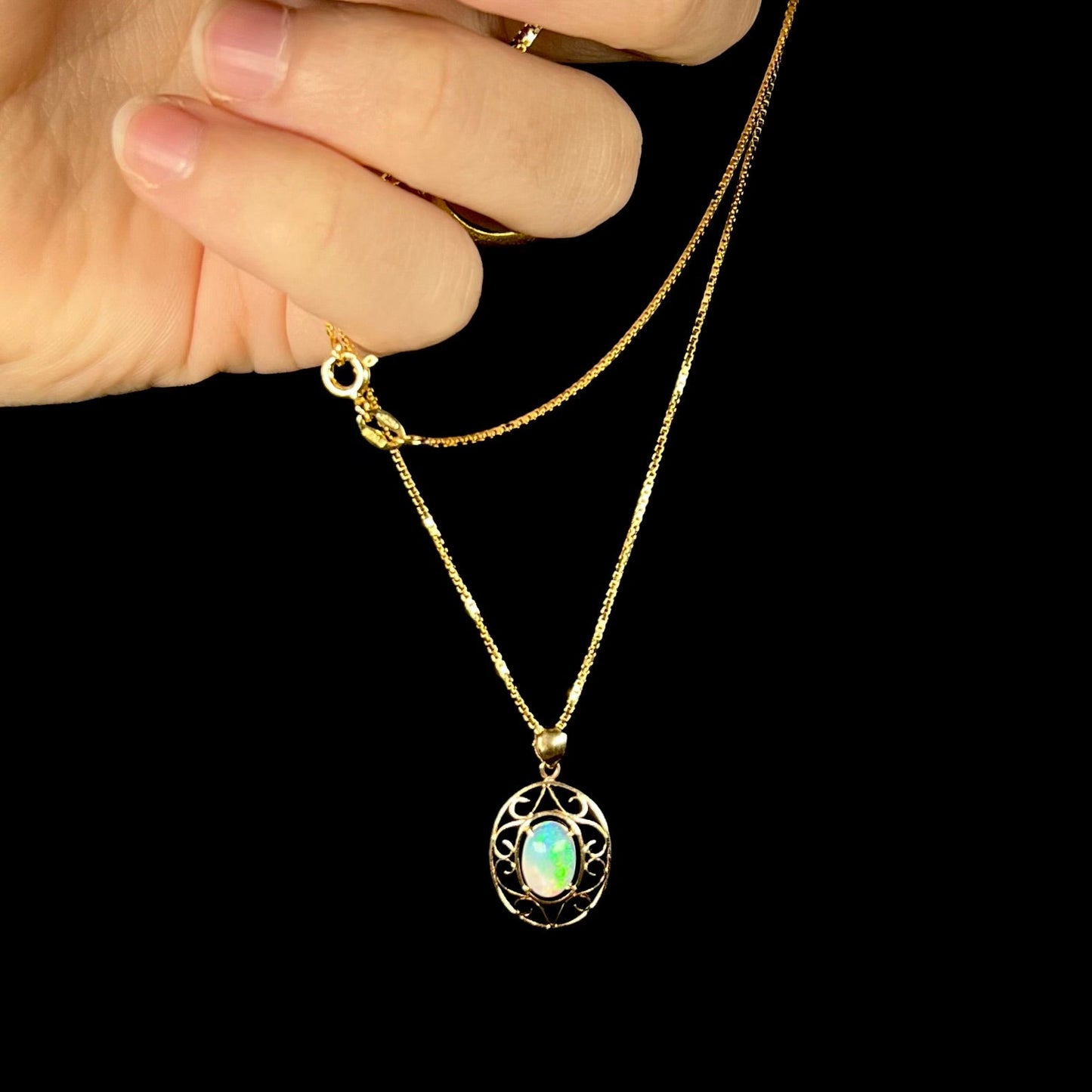 An 18 karat yellow gold filigree opal necklace. The opal has bright green color play.